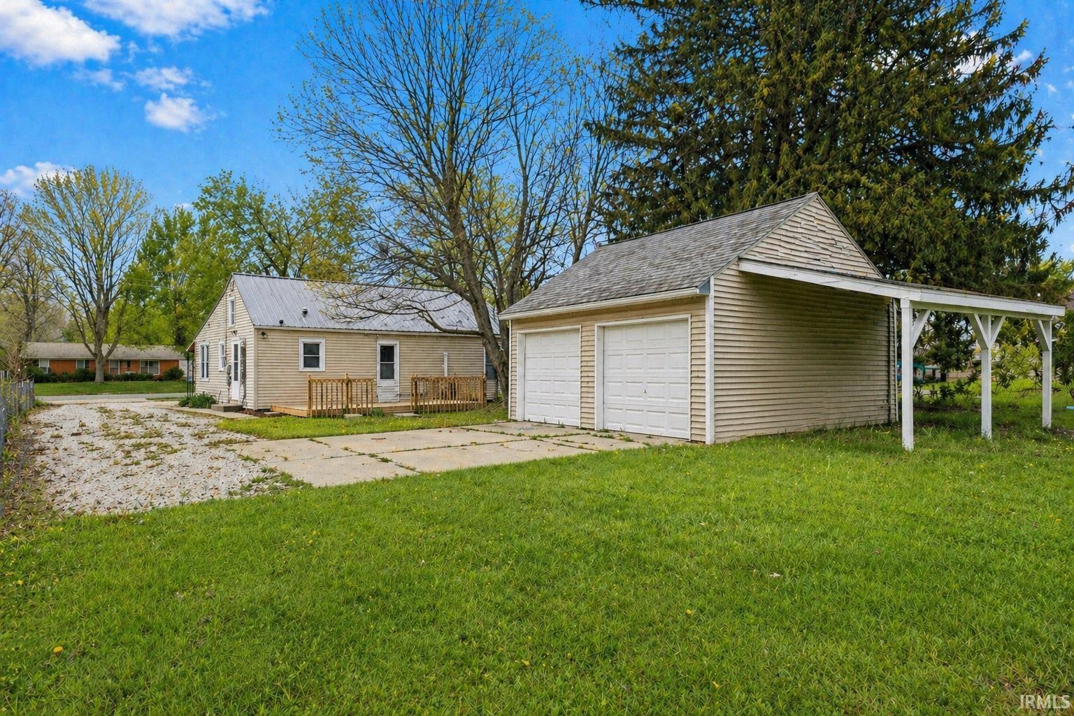 Detached two-car garage with overhead doors and an attached side carport