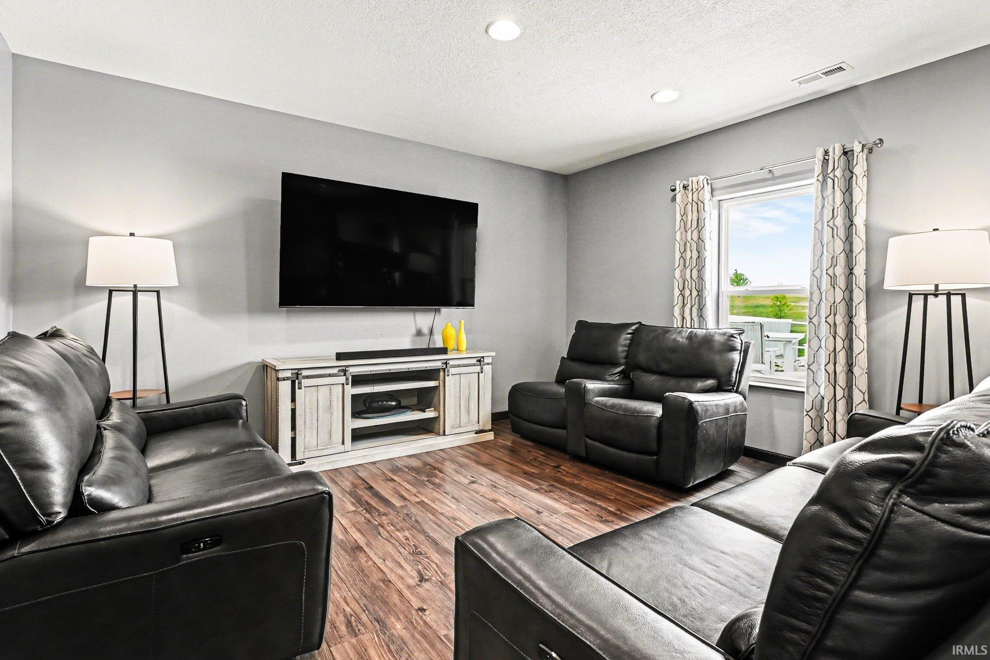 Spacious living area featuring wood-finish flooring, light gray walls, and recessed ceiling lighting