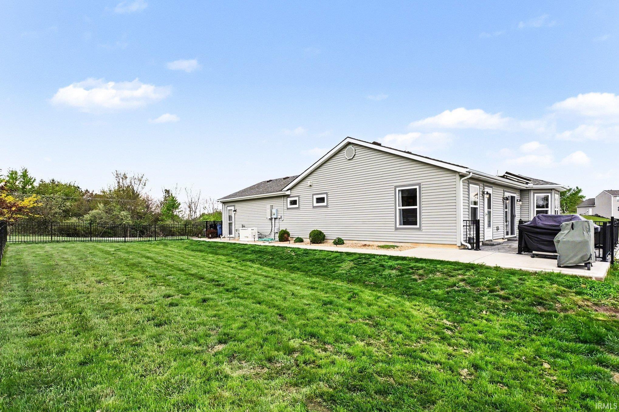 Expansive green lawn with a black metal fence enclosing the perimeter