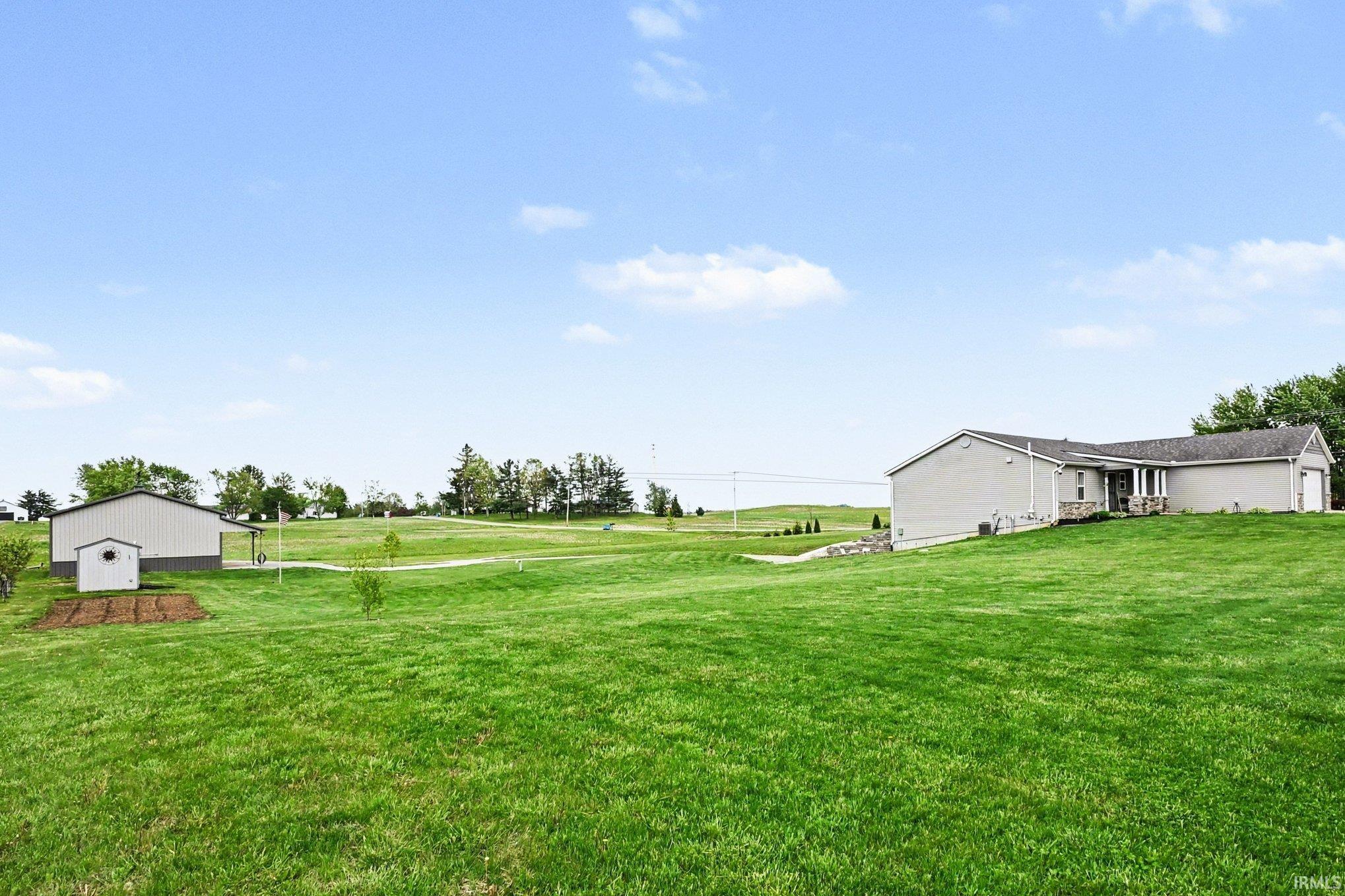Expansive green lawn with a gray exterior residence featuring stone accenting and an attached two-car garage