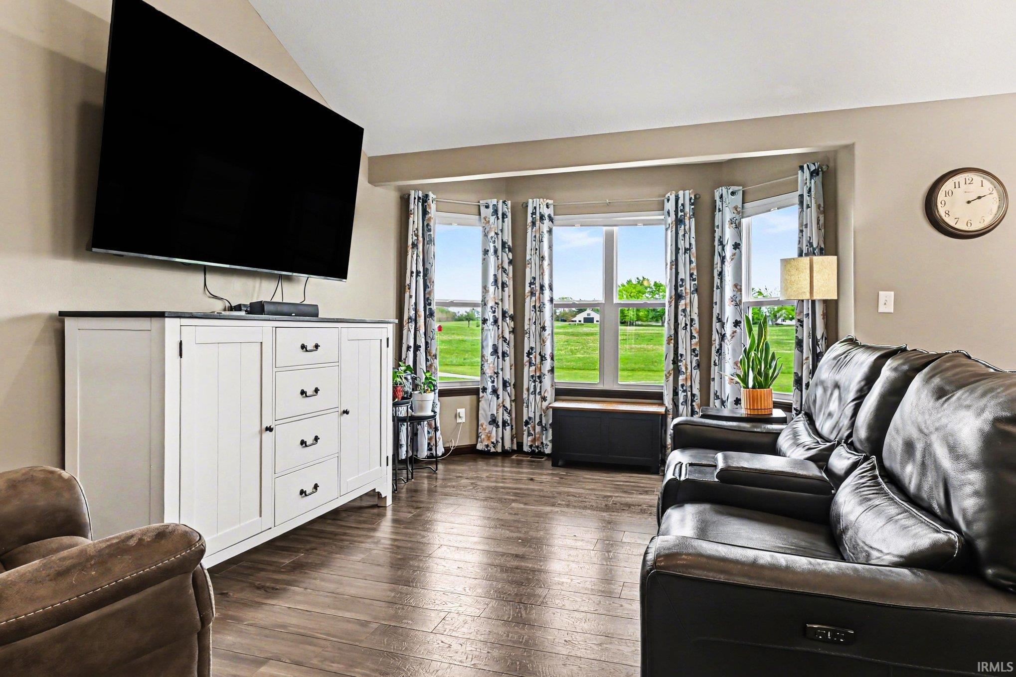 Living area featuring a bay window with a wide outdoor expanse, wood-finish flooring, and a neutral wall color