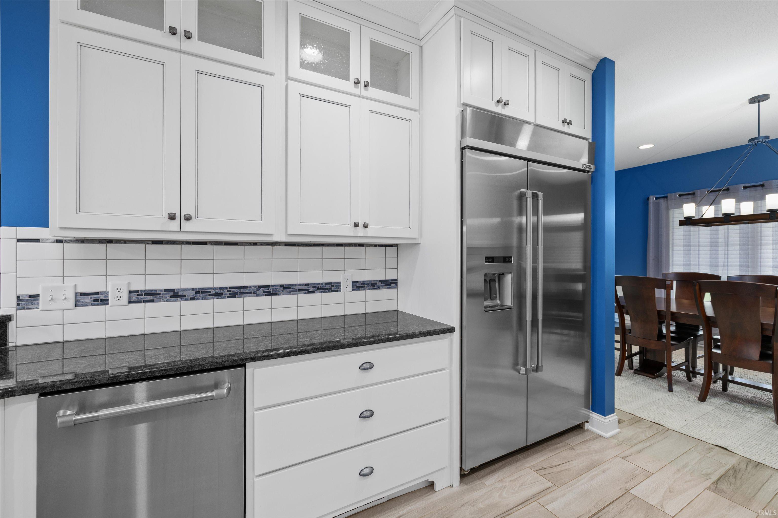 Modern kitchen featuring white cabinetry, a stainless steel refrigerator, and a dishwasher