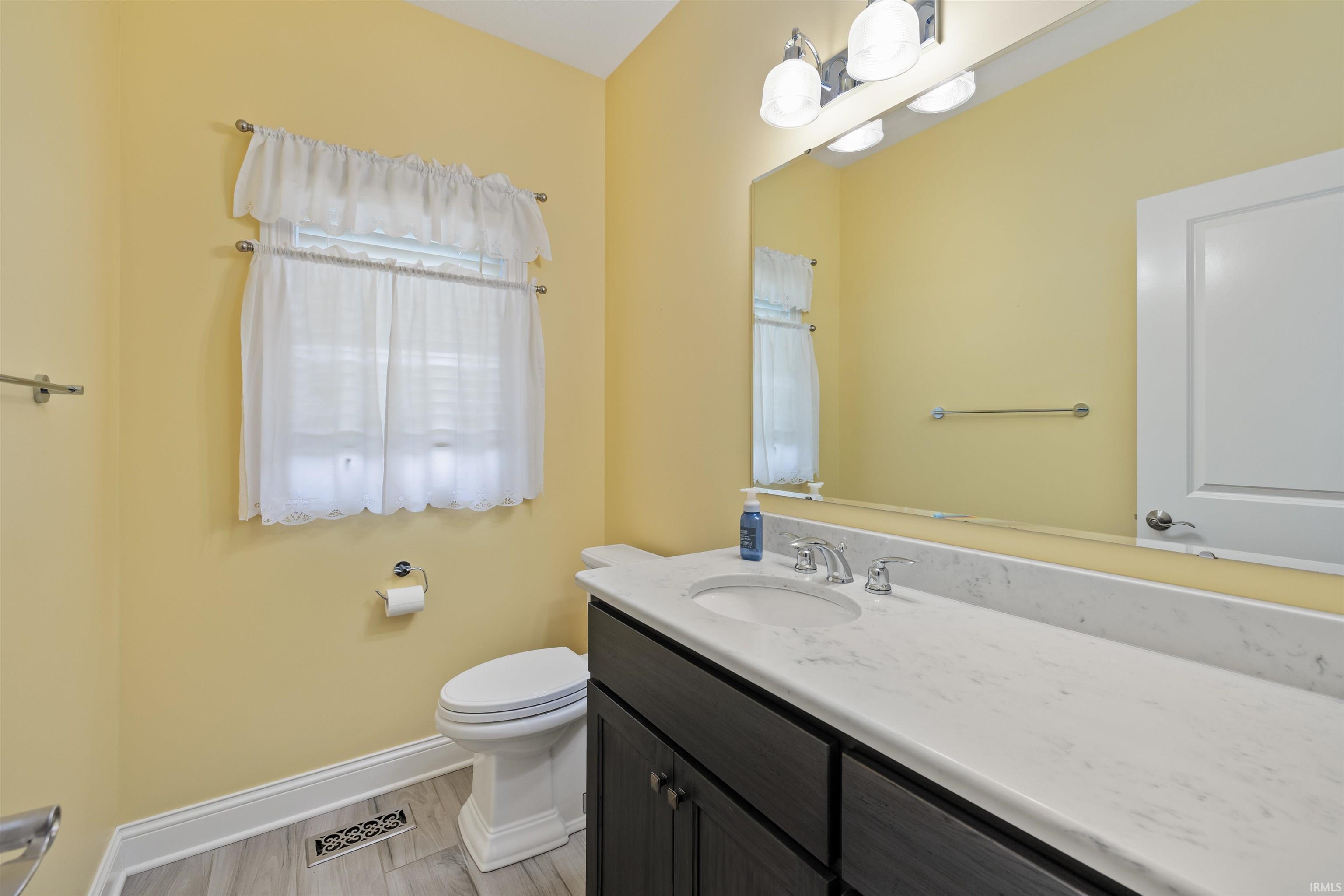 Bathroom vanity featuring an integrated sink with a chrome faucet, a stone-finish countertop, and dark wood-finish cabinetry