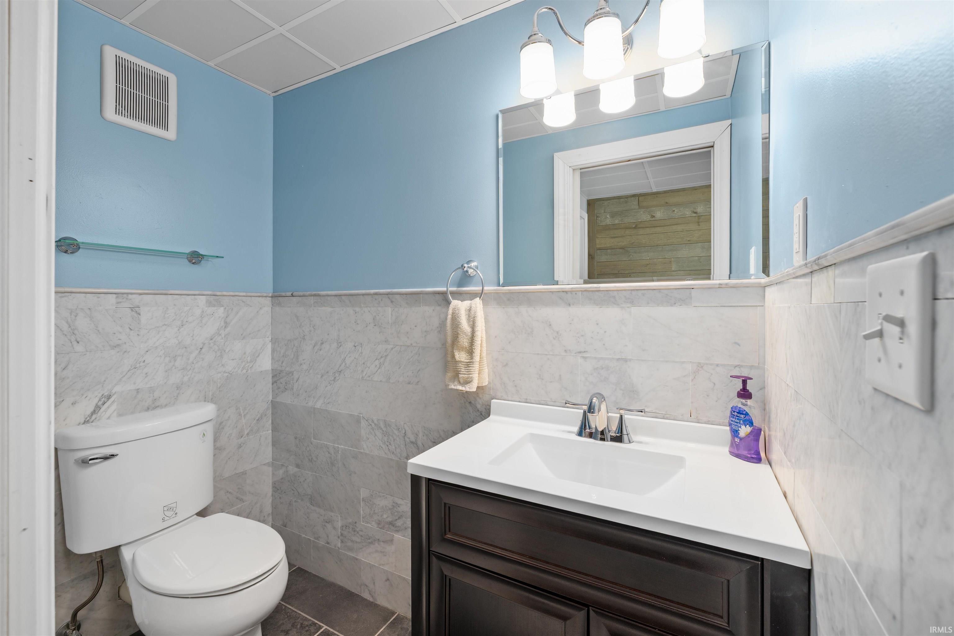 Bathroom featuring a dark wood-finish vanity with a white countertop, chrome faucet, and rectangular sink