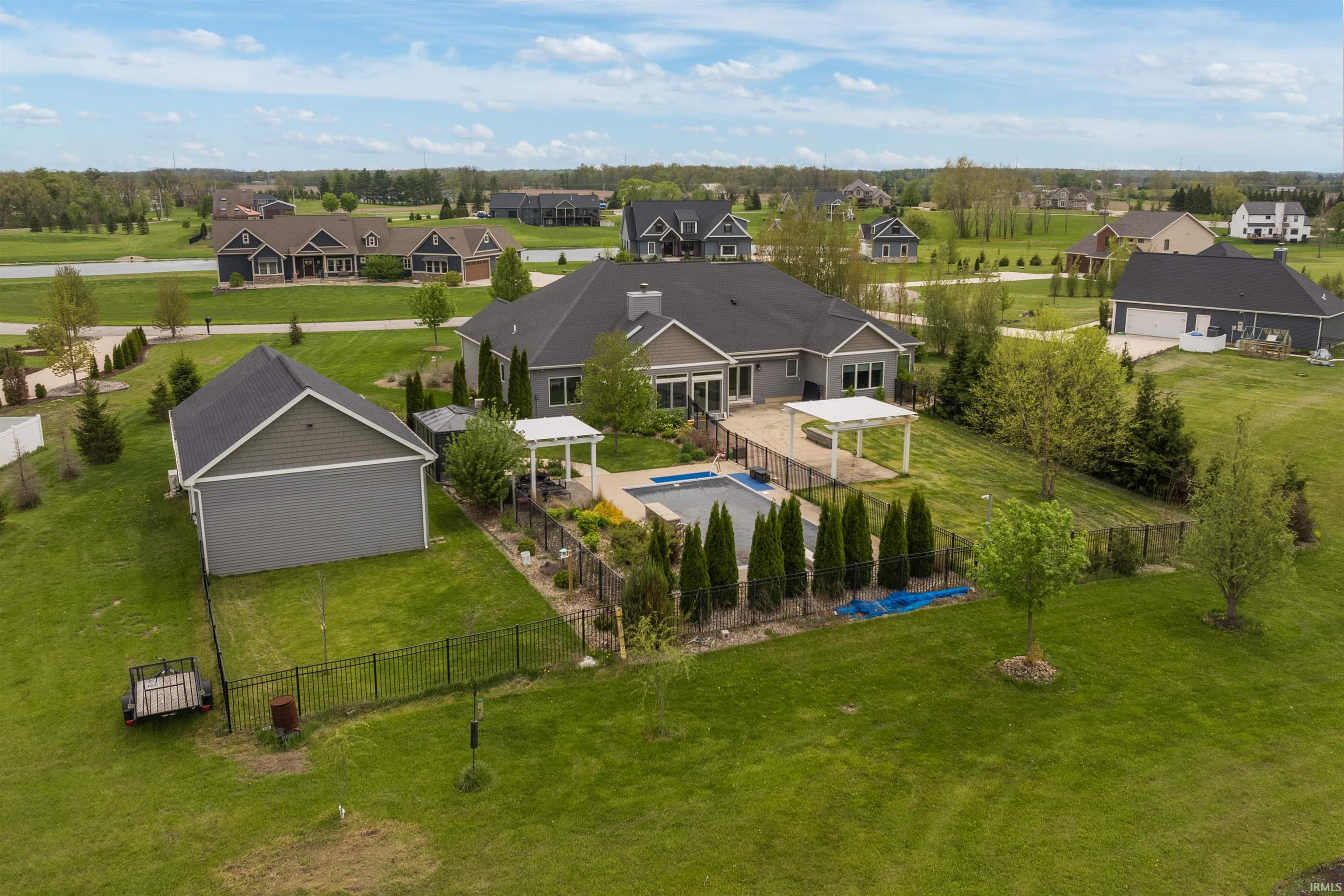 Spacious backyard featuring an in-ground swimming pool, a large patio with a pergola, and mature landscaping