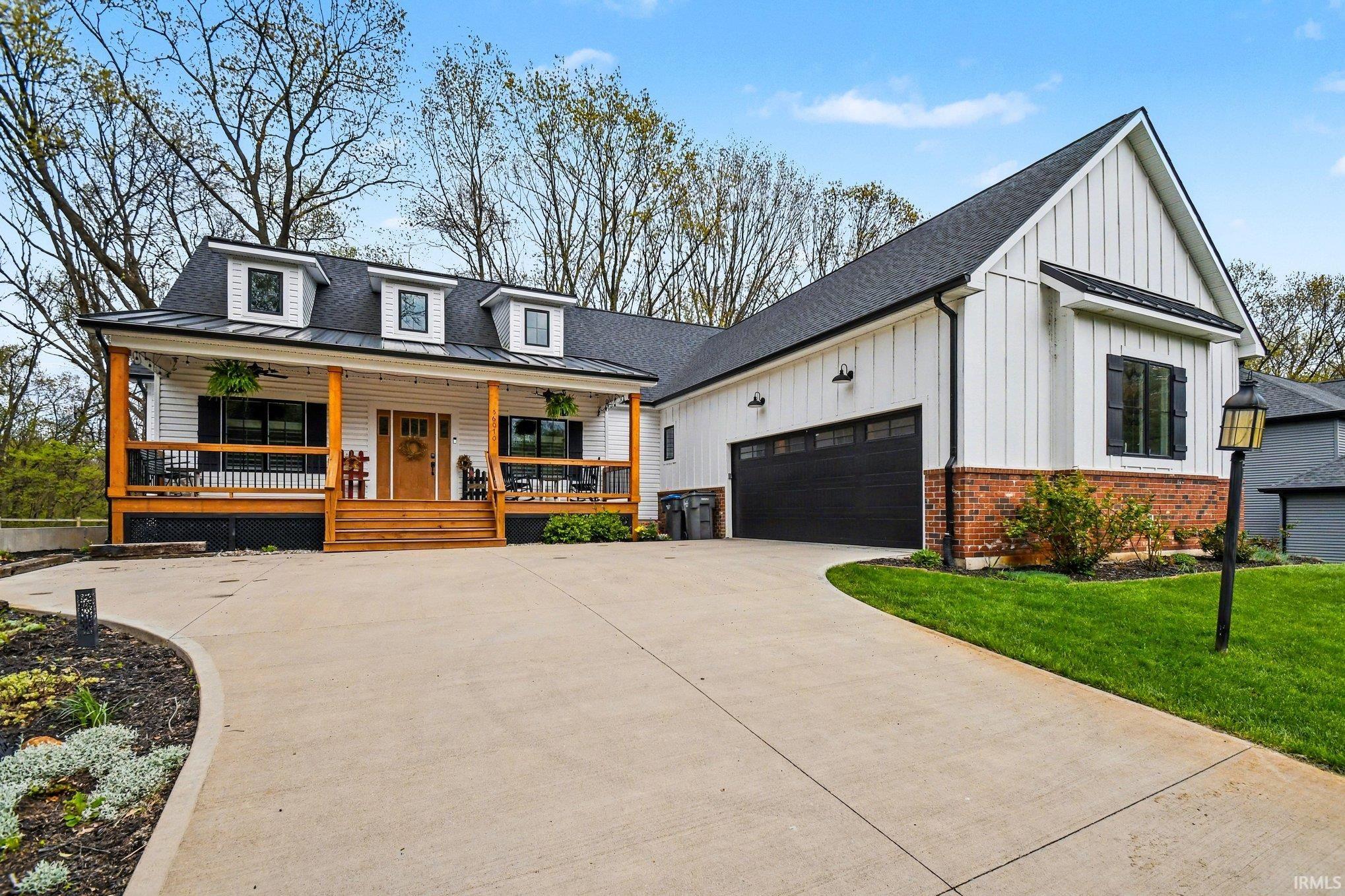 Modern farmhouse exterior with white board and batten siding, black trim, a dark asphalt shingle roof, and a red brick foundation