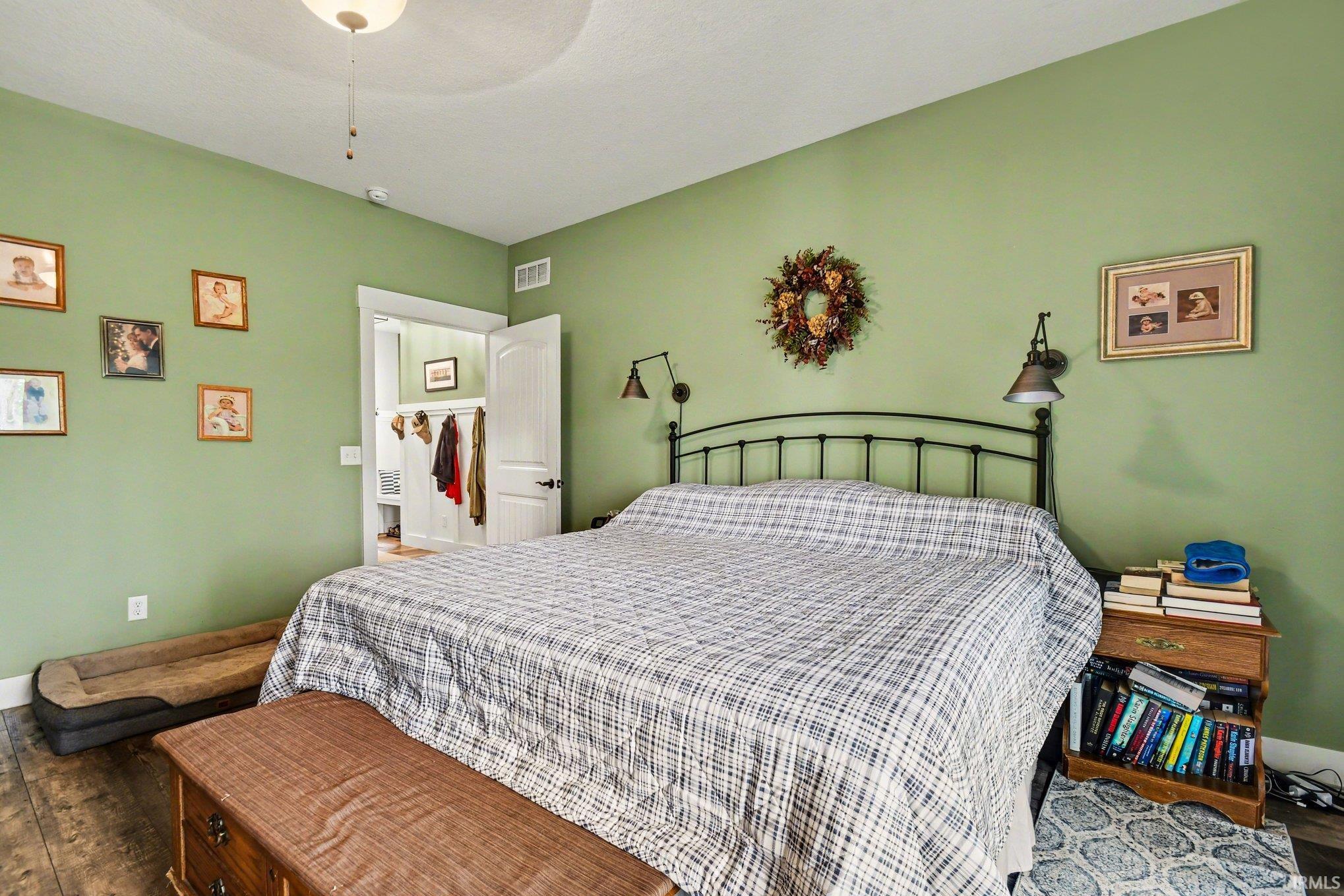 Bedroom featuring a tray ceiling with a flush-mount light fixture, wood-finish flooring, a white paneled door, and an open entryway to a closet with built-in storage