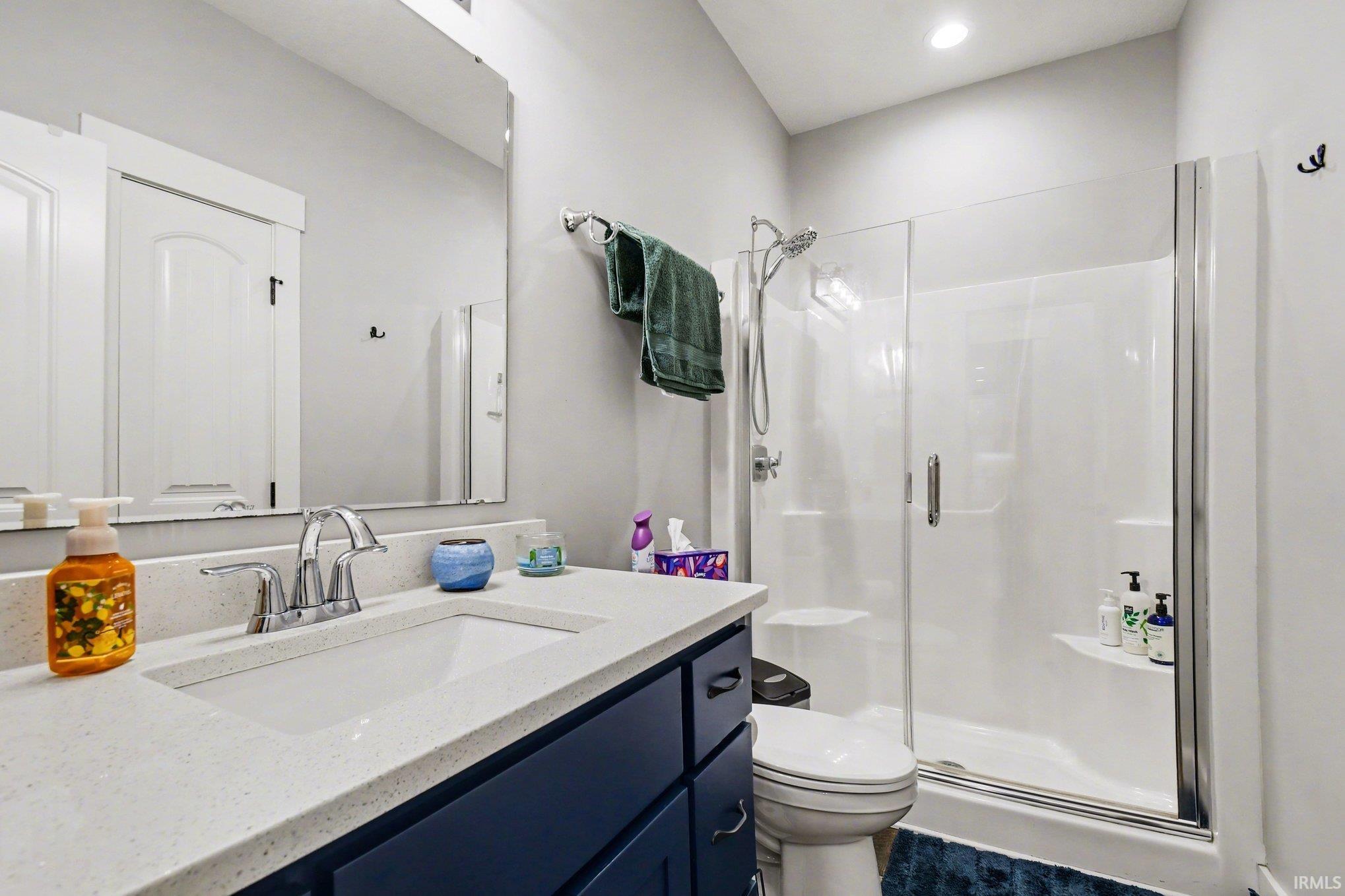 Full bathroom featuring a single vanity, a built-in shower stall with a glass enclosure, a white toilet, and recessed lighting