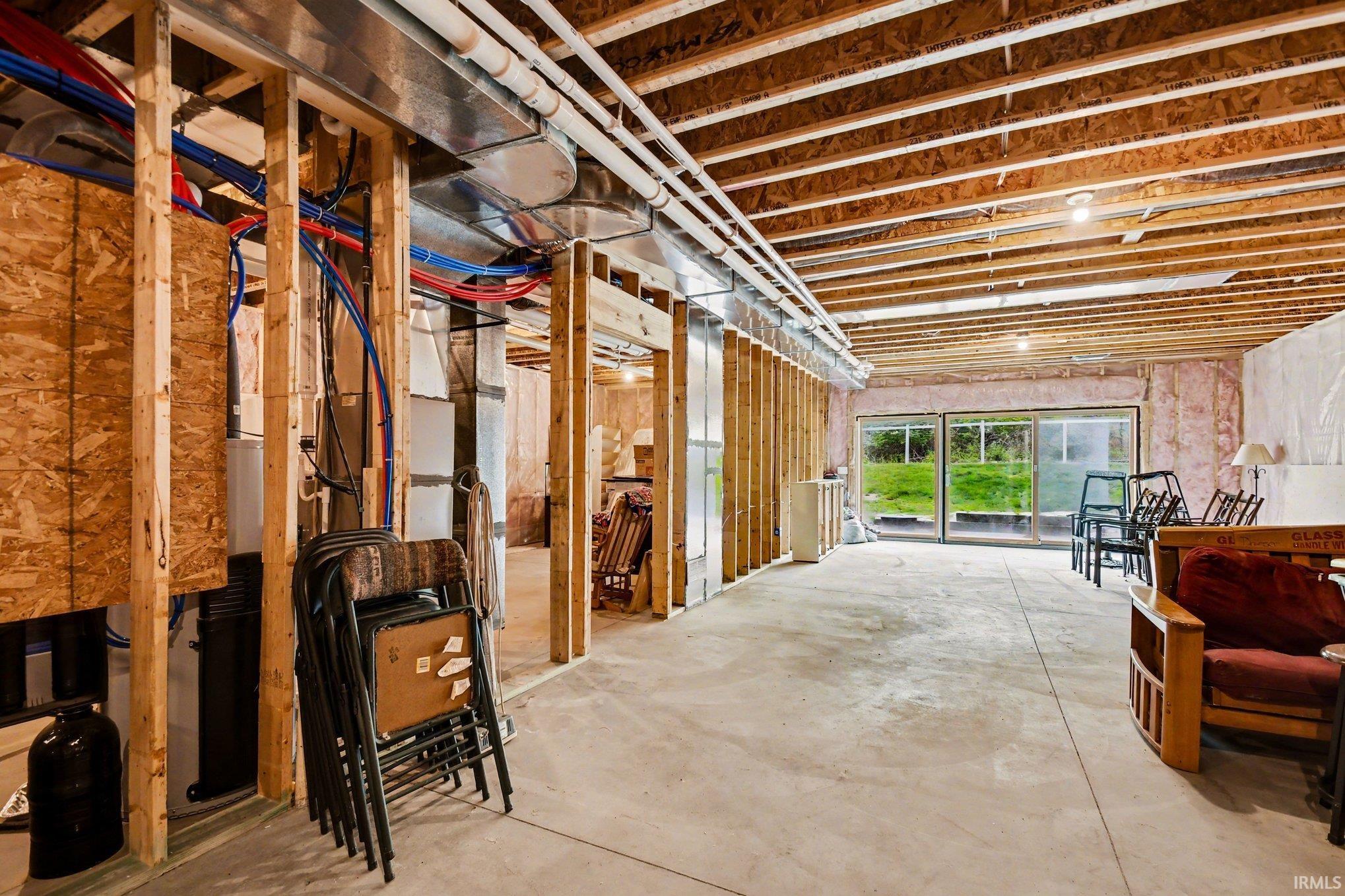 Unfinished lower level with concrete flooring, exposed ceiling joists, and a sliding glass door providing exterior access