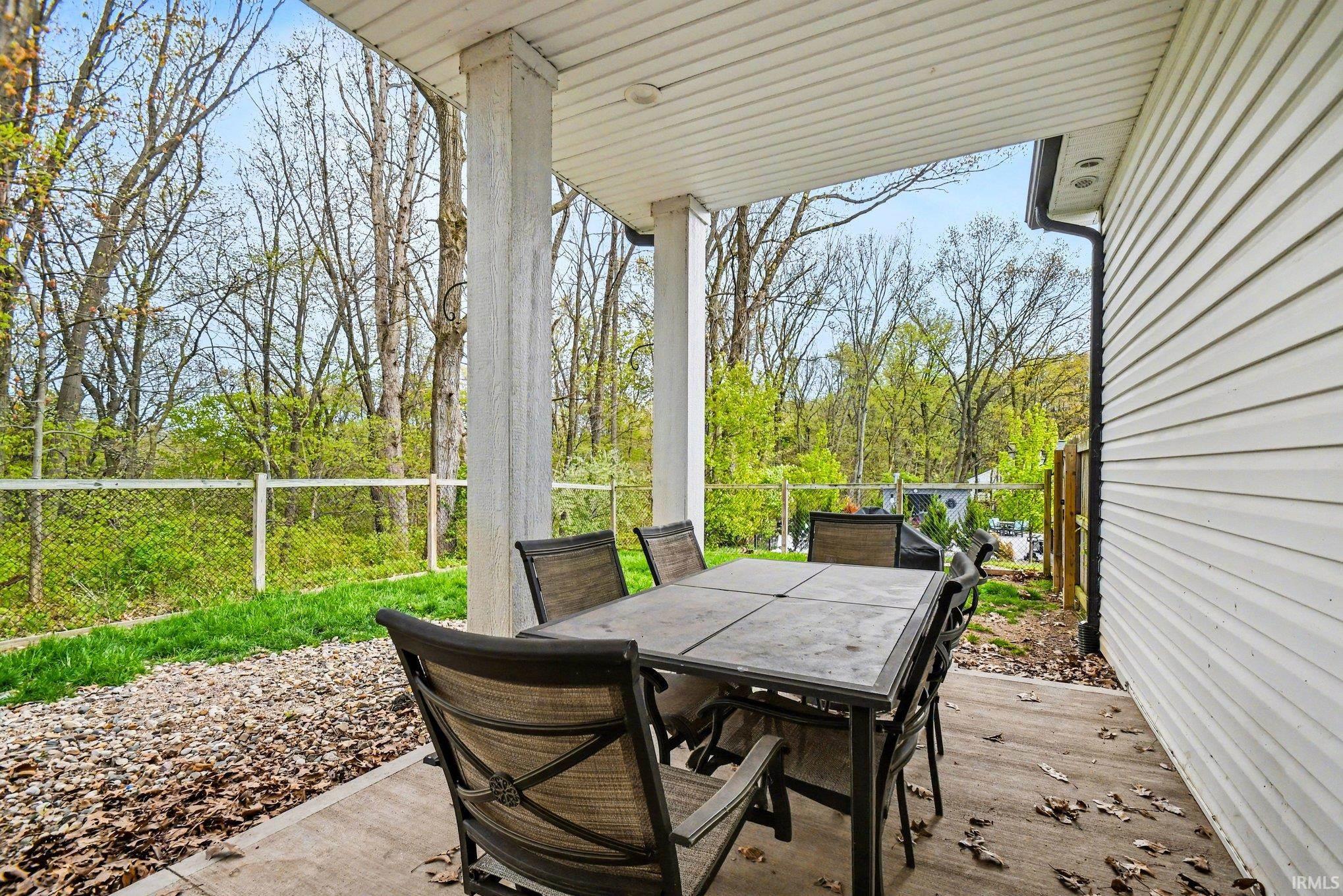 Covered concrete patio with white vinyl siding exterior and white columns