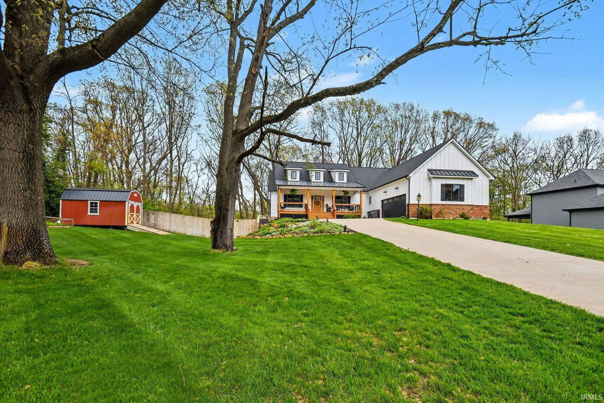 Contemporary farmhouse-style residence featuring white board-and-batten siding with black trim, a gabled roofline, and dormer windows