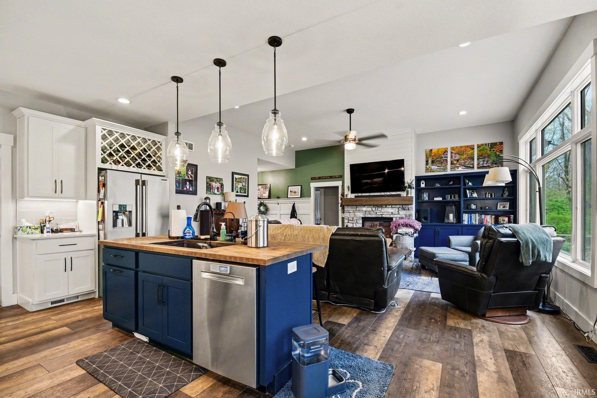 Open-concept living space featuring wood-finish flooring, a kitchen island with a wood countertop, and pendant lighting