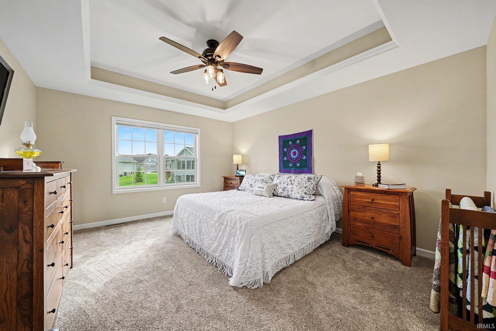 Spacious room featuring a tray ceiling, ceiling fan, and neutral wall paint