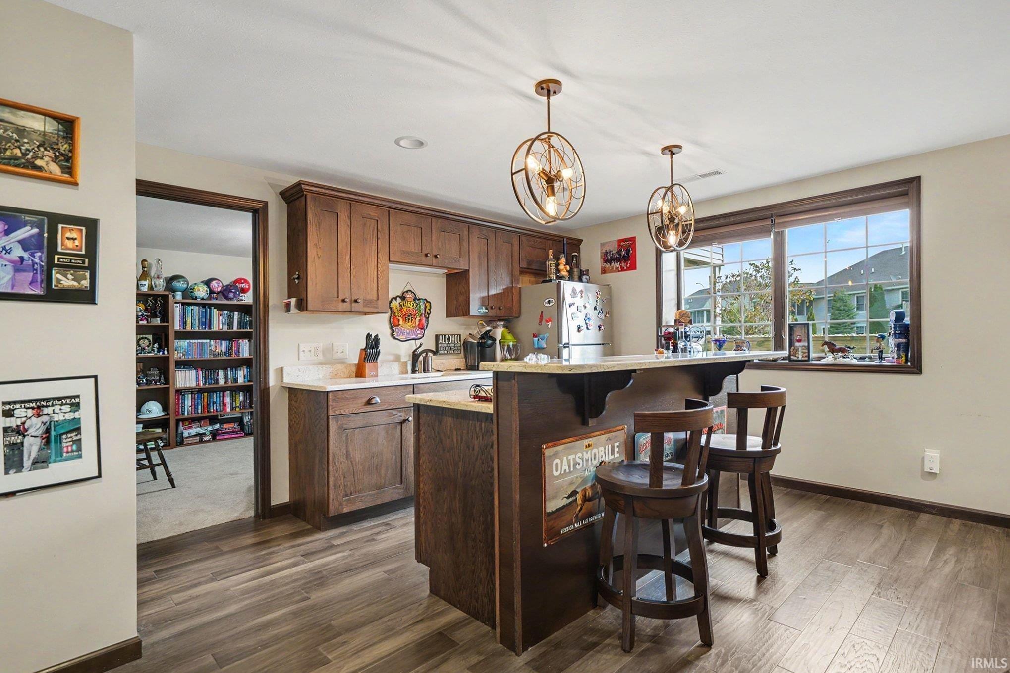 Kitchenette featuring wood-finish flooring, warm wood cabinetry, and light countertops