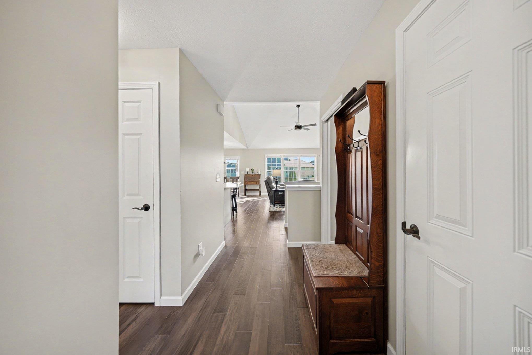 Entryway featuring wood-finish flooring, light neutral wall tones, white trim, and a built-in hall tree with storage and a stone-look bench