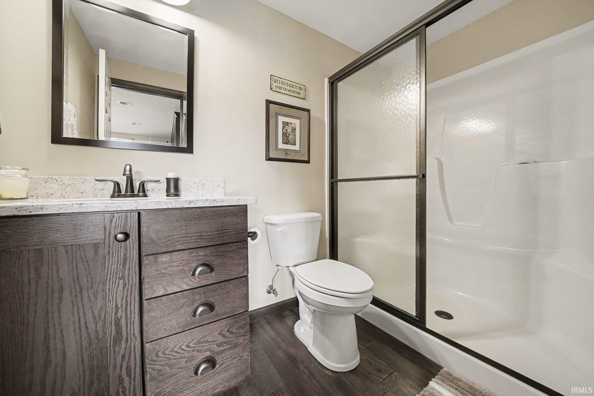 Bathroom featuring a wood-finish vanity with a light-colored countertop, a rectangular framed mirror, and a toilet
