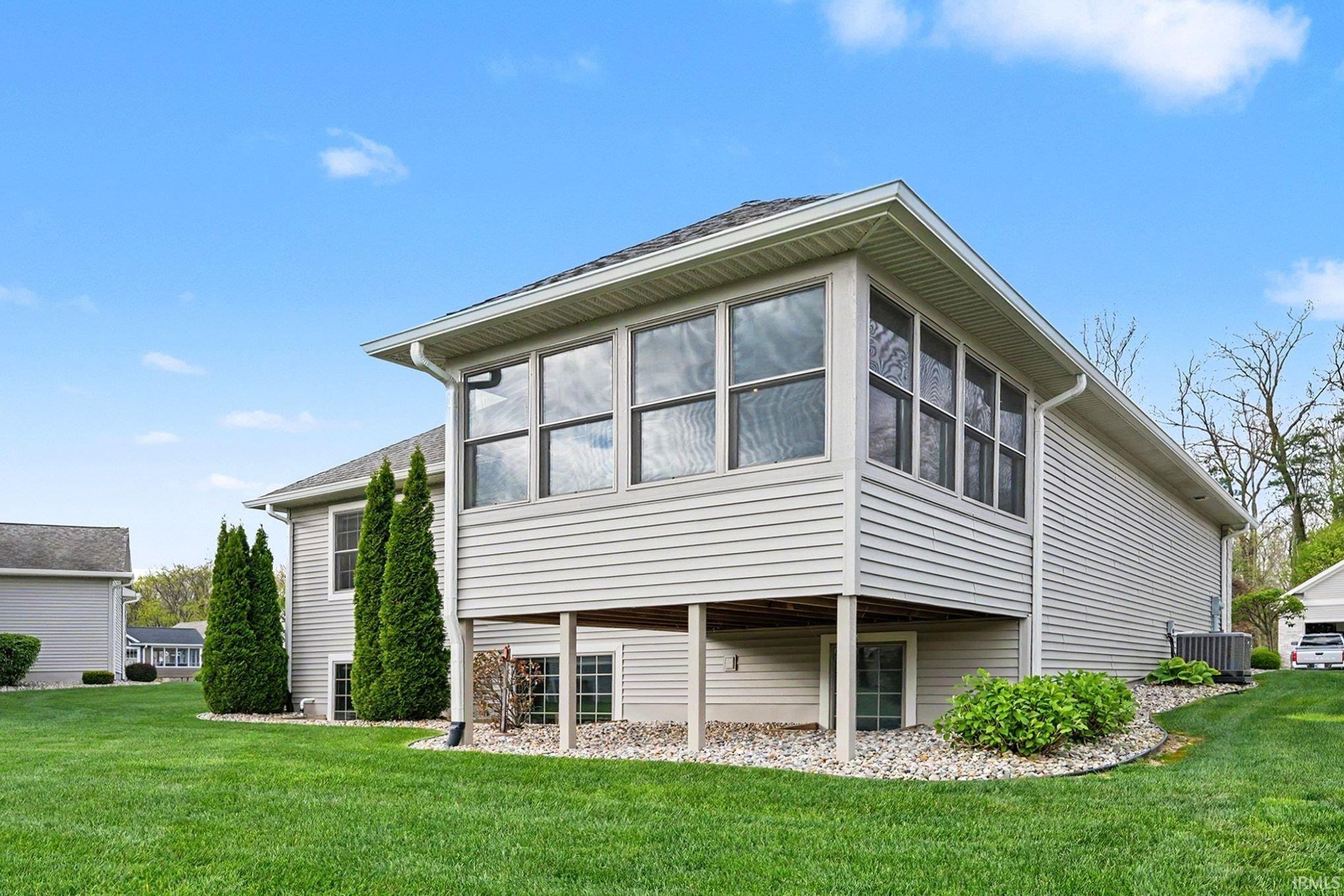 Expansive green lawn surrounds the property featuring light-colored siding