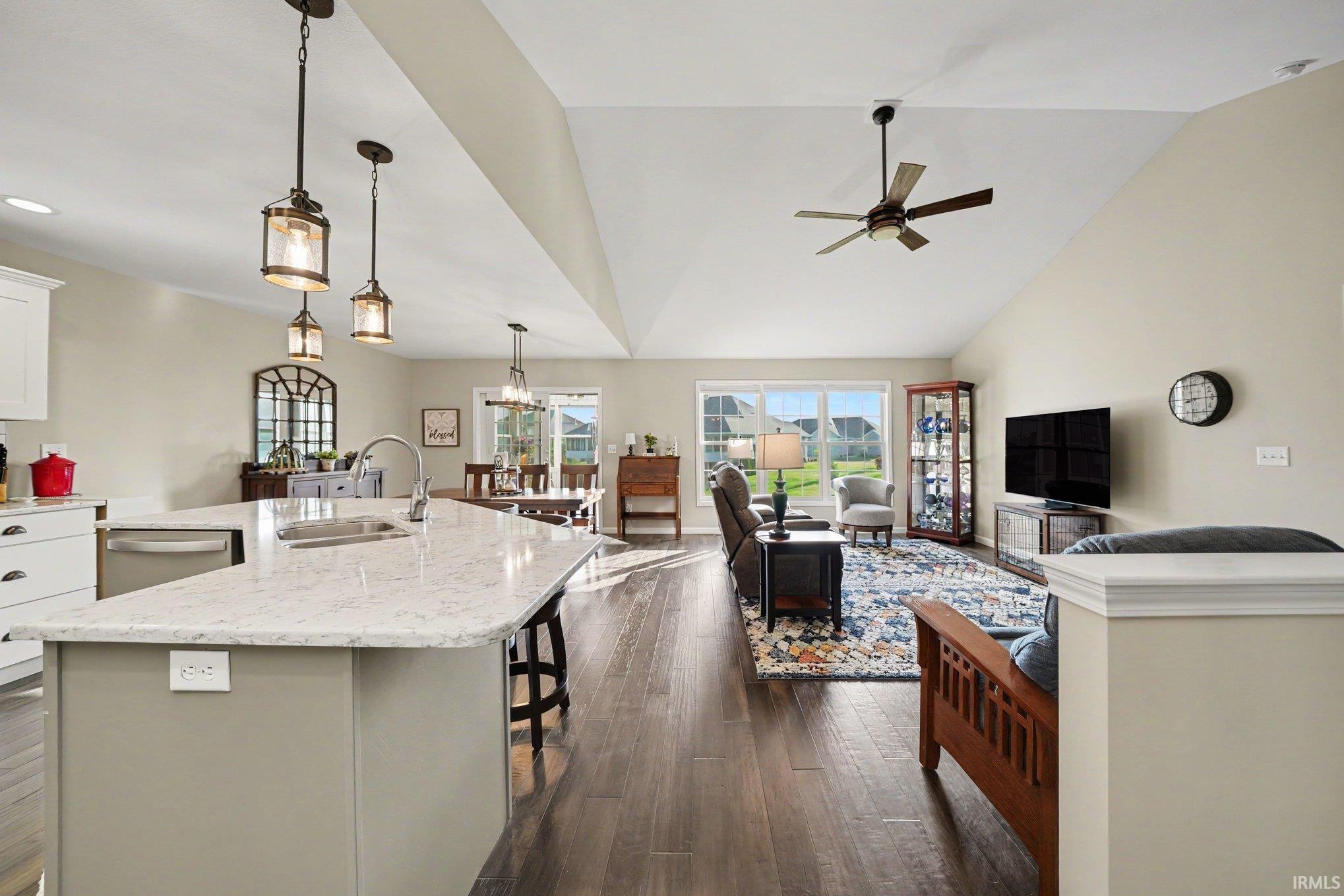 Open-concept living space featuring wood-finish flooring, vaulted ceilings, and large windows