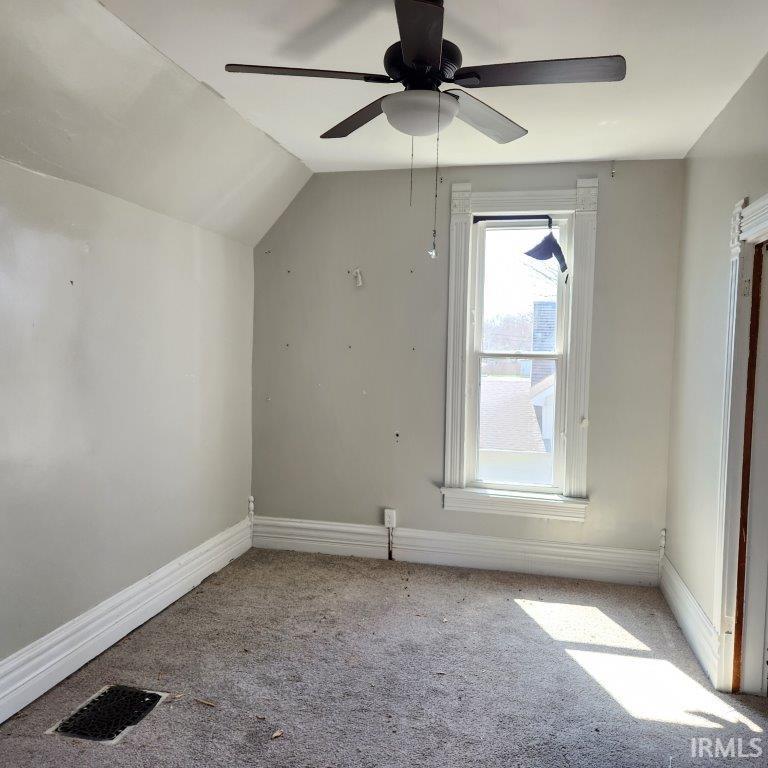 Room featuring a ceiling fan with integrated lighting, a double-hung window with decorative trim, and wall-to-wall carpeting