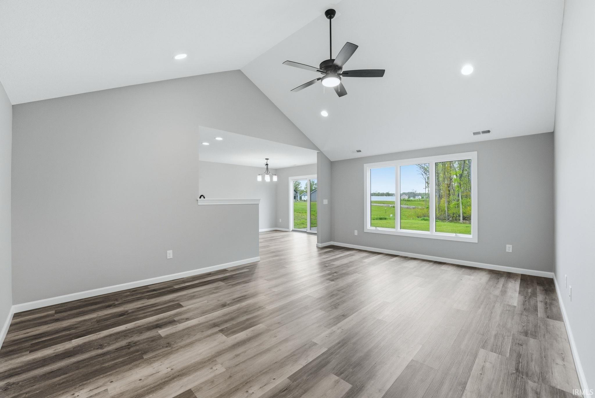 Spacious living area featuring vaulted ceilings, wood-finish flooring, recessed lighting, and a contemporary ceiling fan