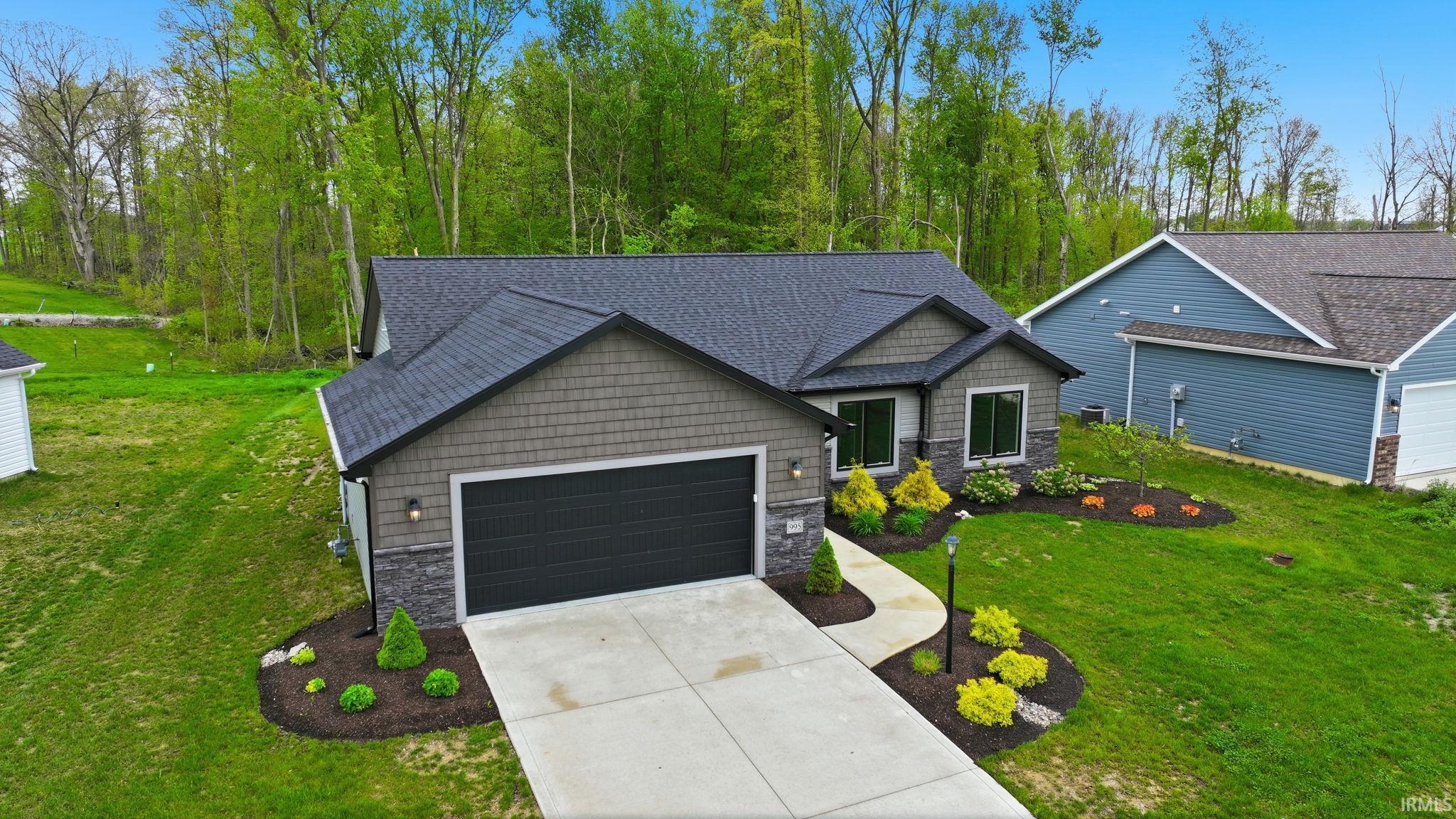 Contemporary single-story residence featuring a dark asphalt shingle roof, gray shaker-style siding, and stone veneer accents