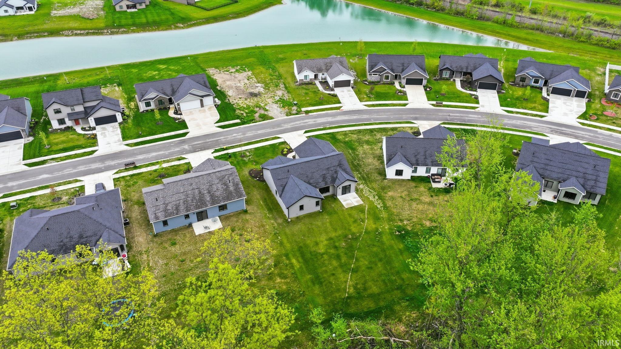Residential development featuring a curved street, multiple single-family homes with dark roofs, and light-colored driveways