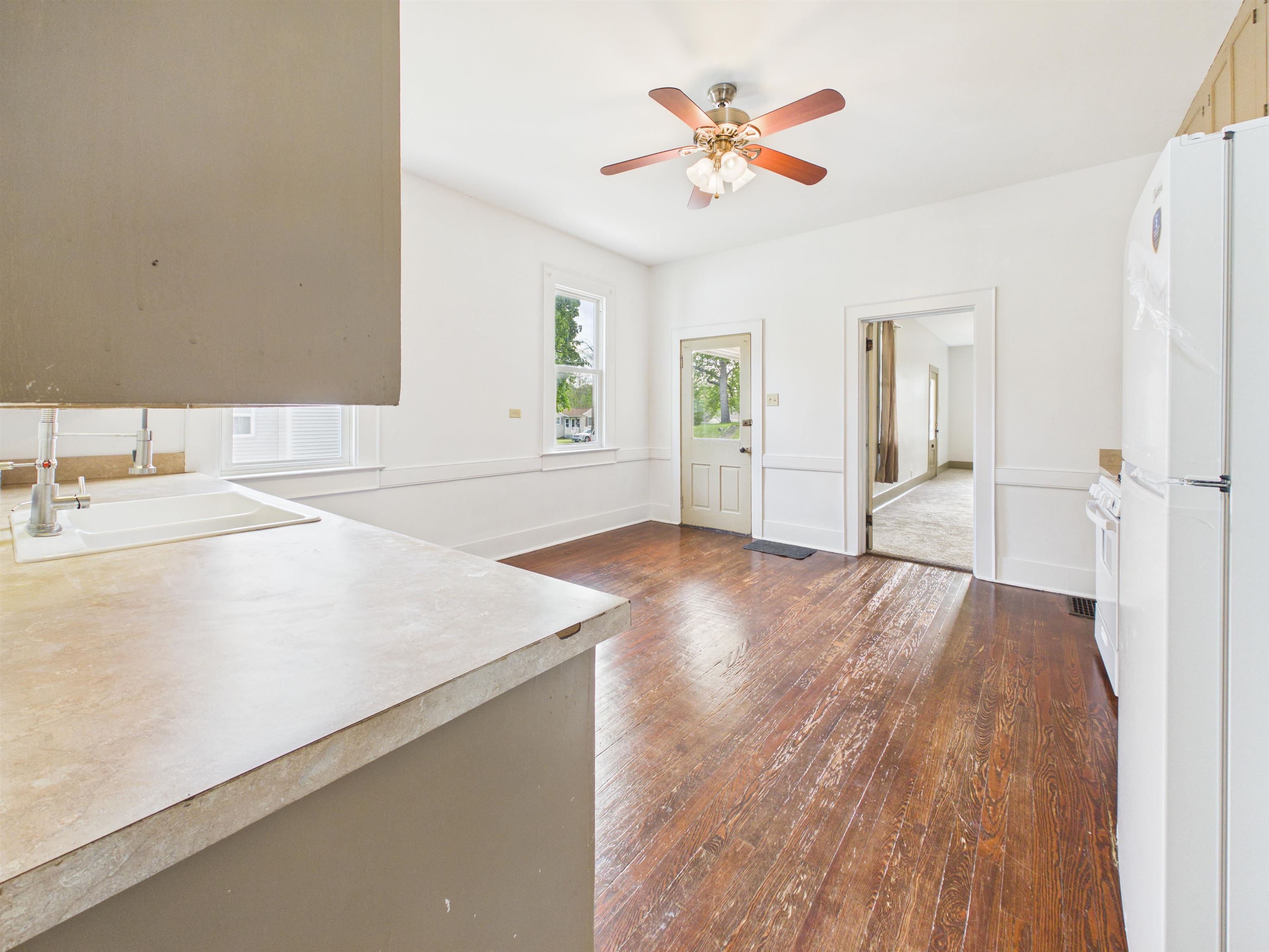 Kitchen area featuring wood-finish flooring, white walls, and a ceiling fan