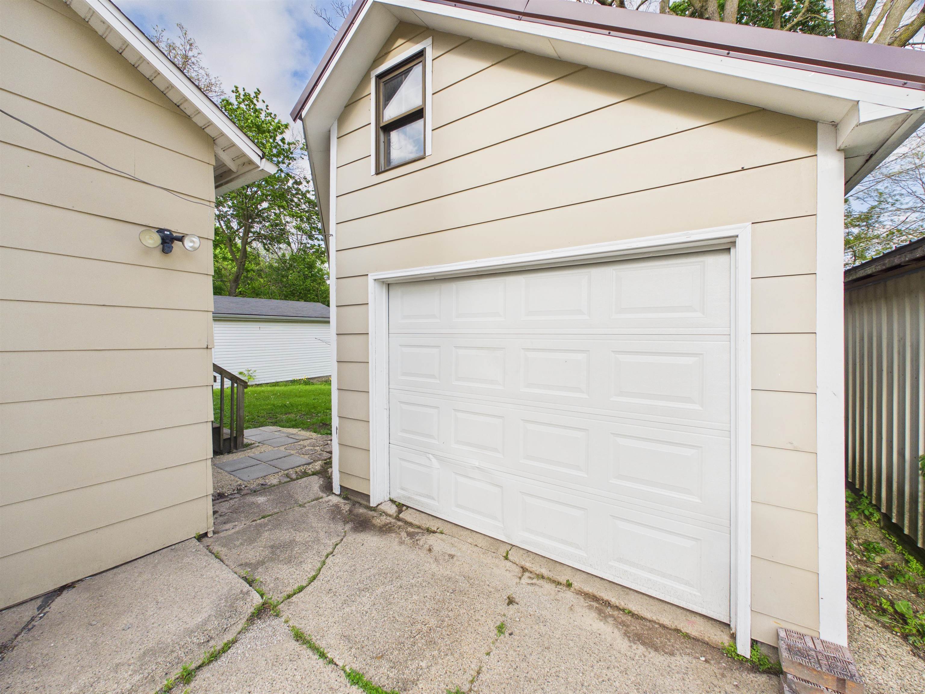 Detached garage structure featuring light-toned horizontal siding and a white paneled garage door