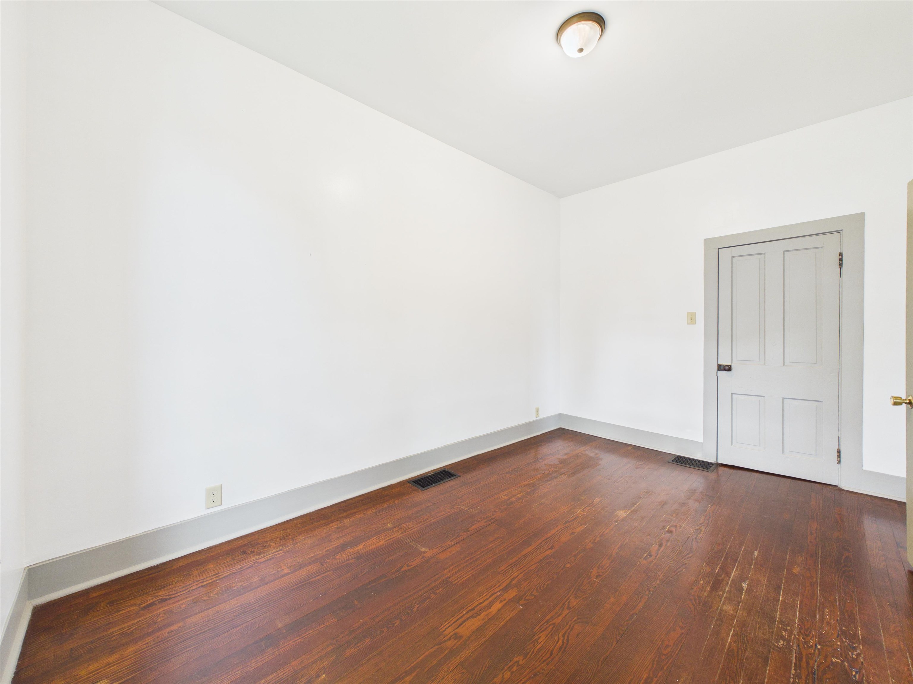 Wood-finish flooring in a neutral-toned room with a paneled door