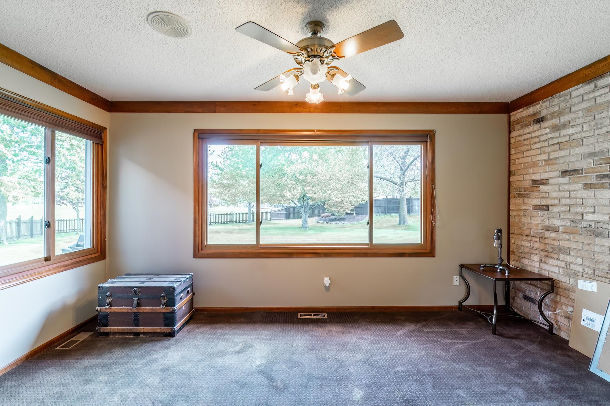 Spacious room featuring multiple windows with wood-finish trim, a textured ceiling, and a ceiling fan with light fixture