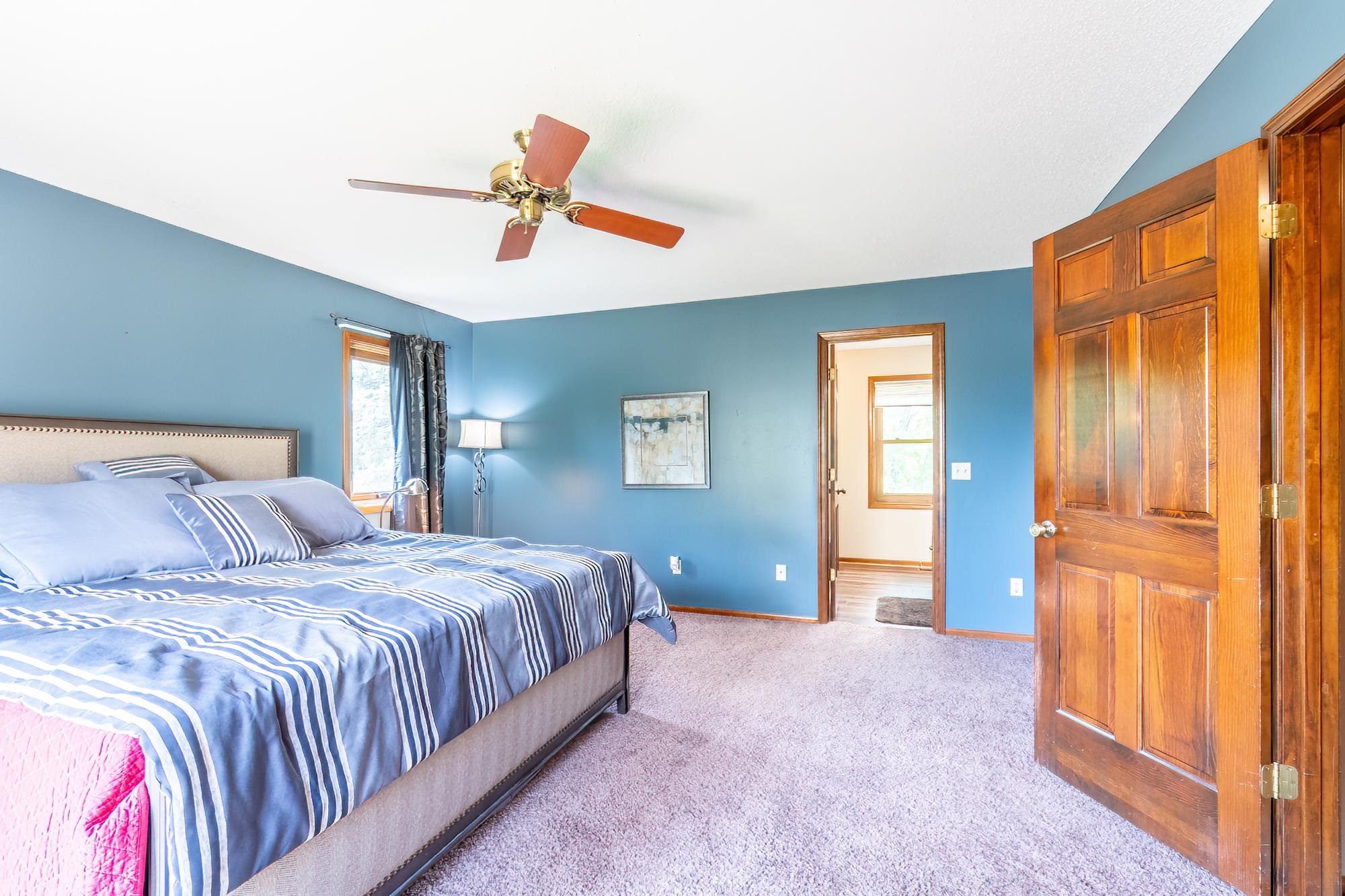 Spacious room featuring a ceiling fan, window with trim, and two paneled doors with hardware