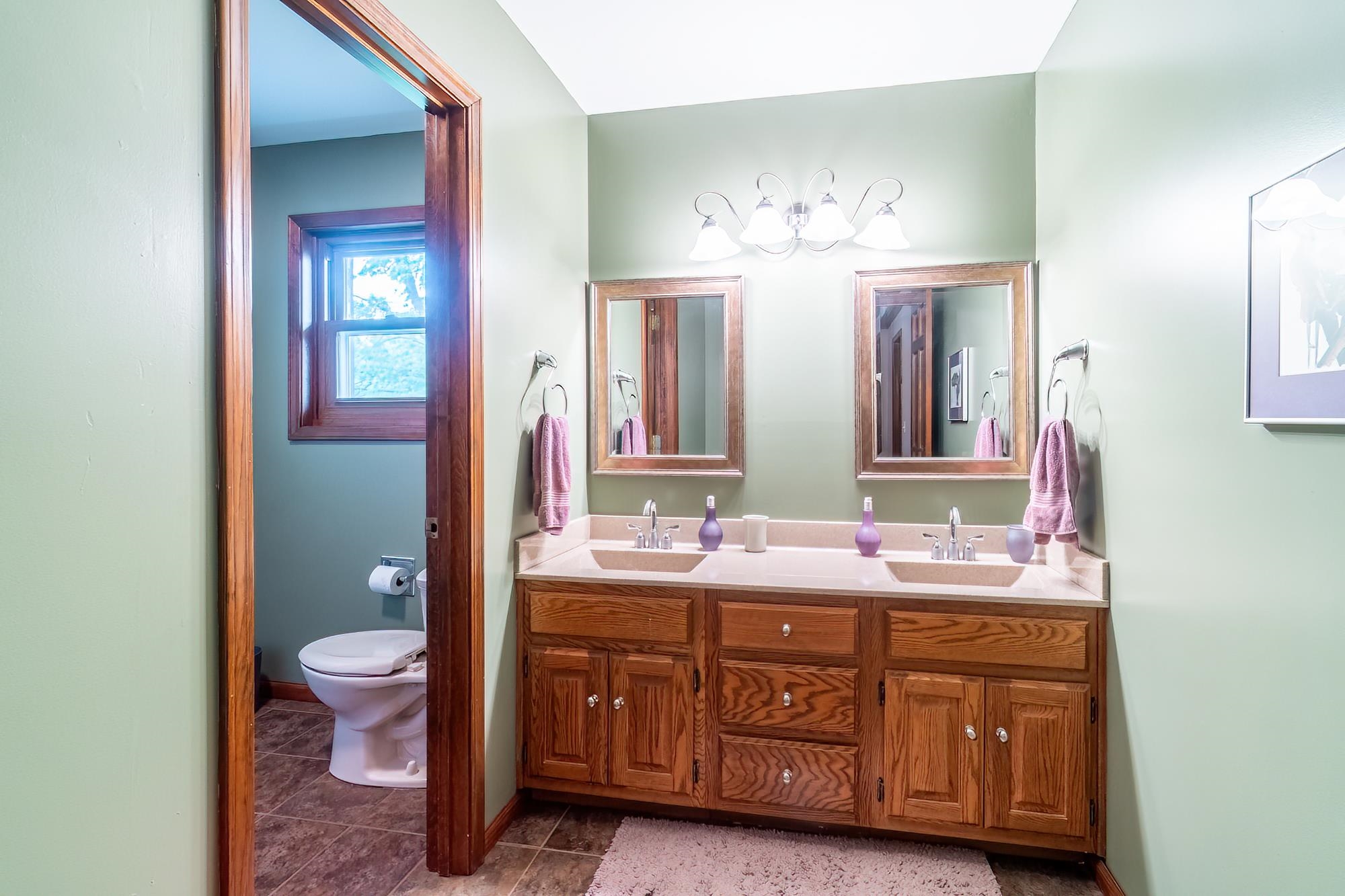 Double vanity with wood-finish cabinetry, integrated sinks, and individual mirrors