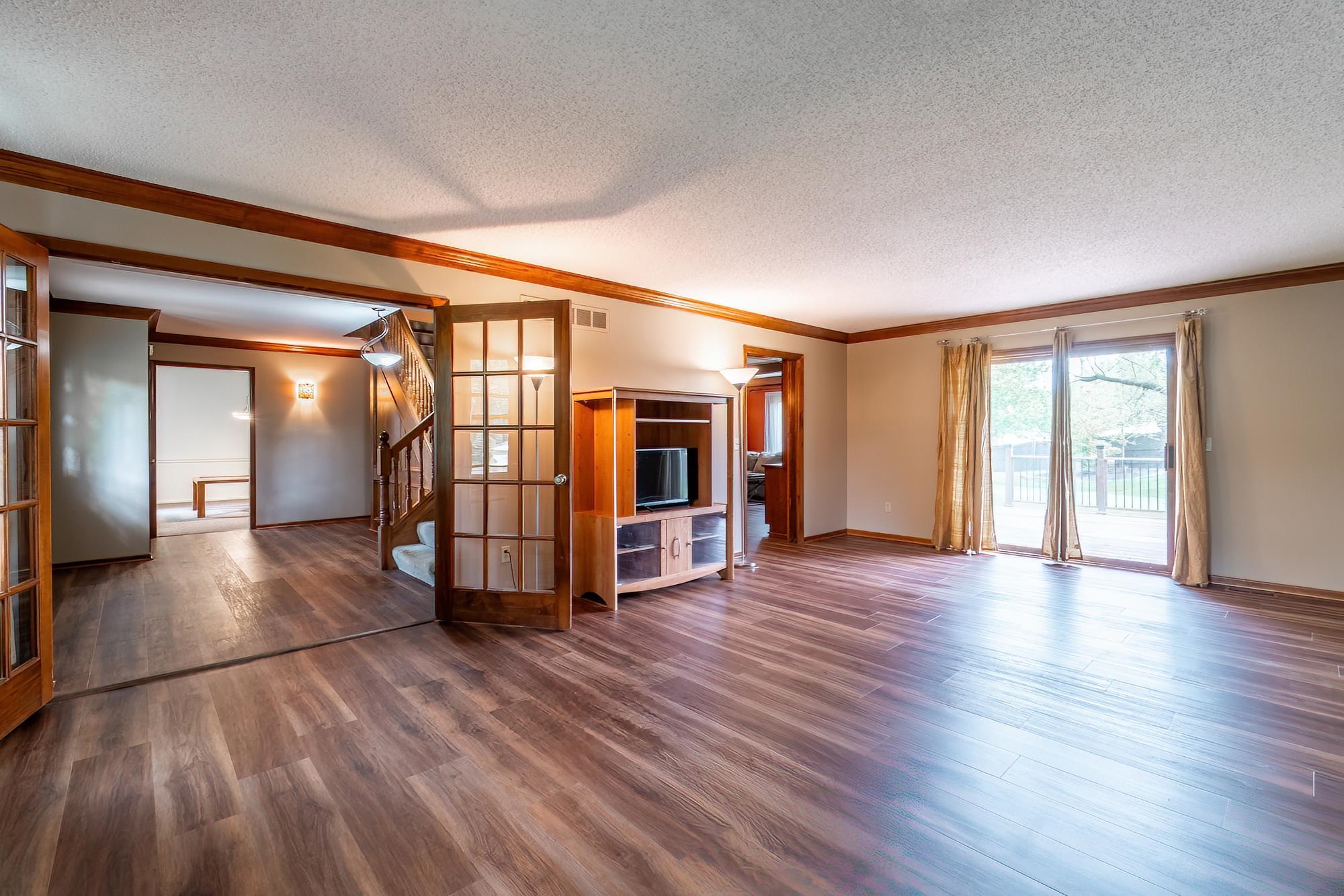 Spacious living area featuring wood-finish flooring, warm wall tones, and crown molding