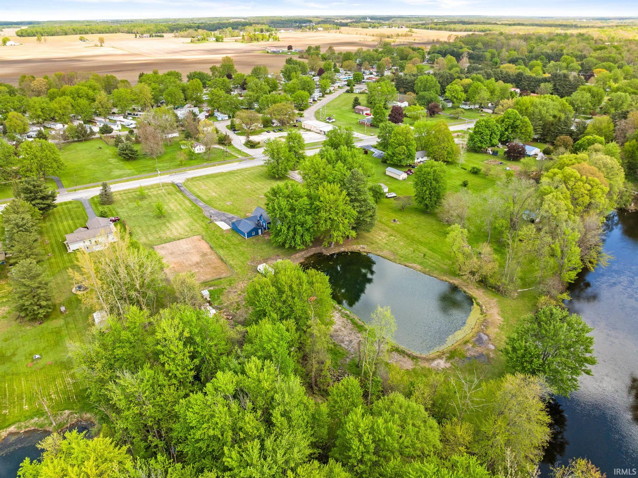 Aerial perspective showcasing a property featuring a private pond and a deep blue residence