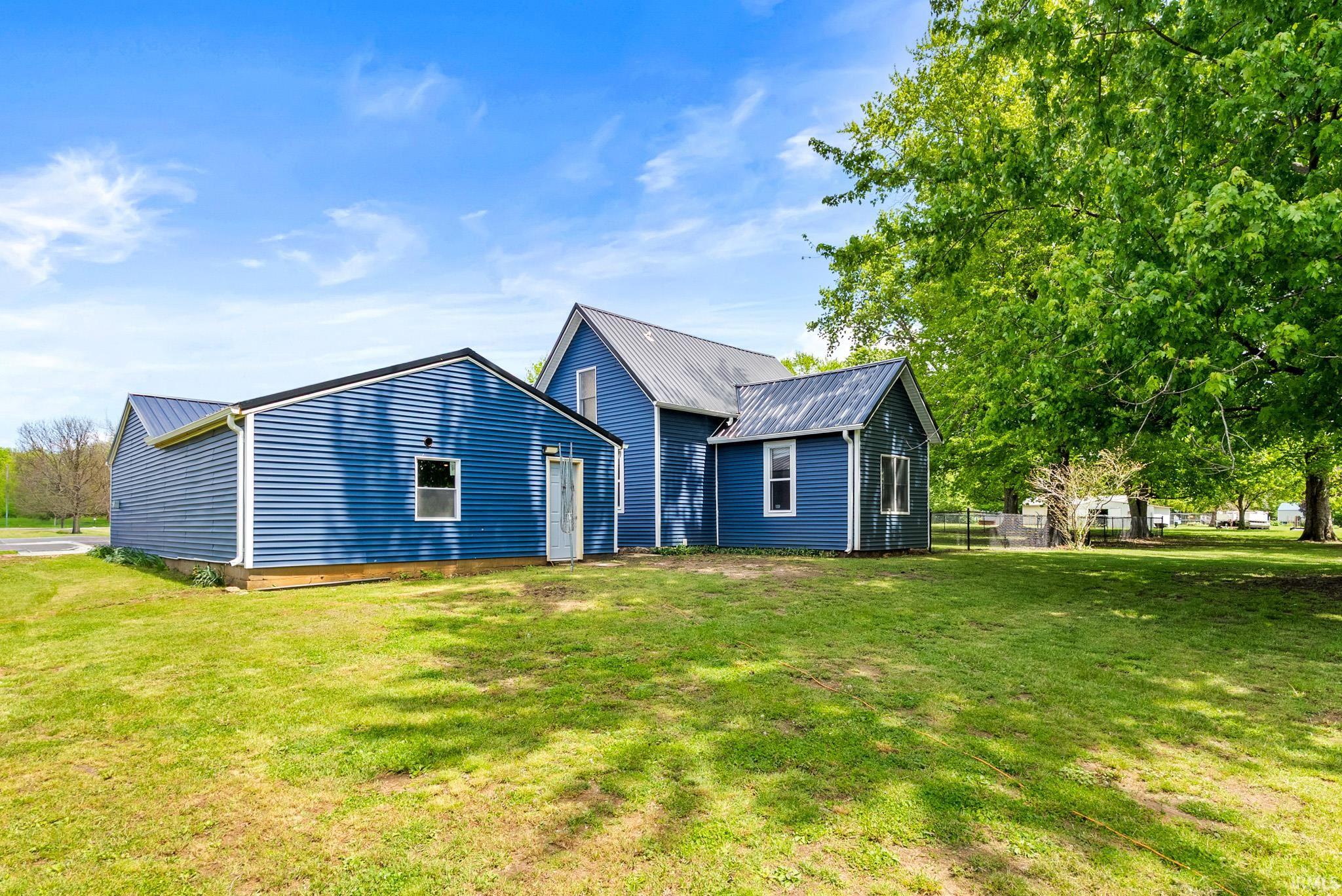 Exterior featuring blue horizontal siding, white trim, and a dark metal roof
