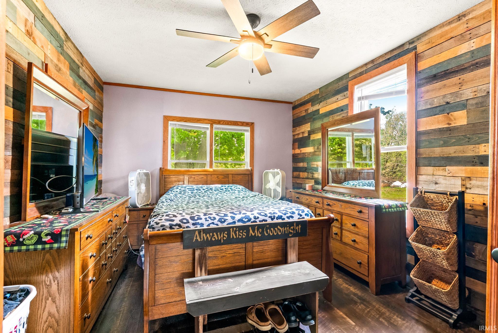 Bedroom featuring wood-finish flooring and two walls with horizontal wood paneling