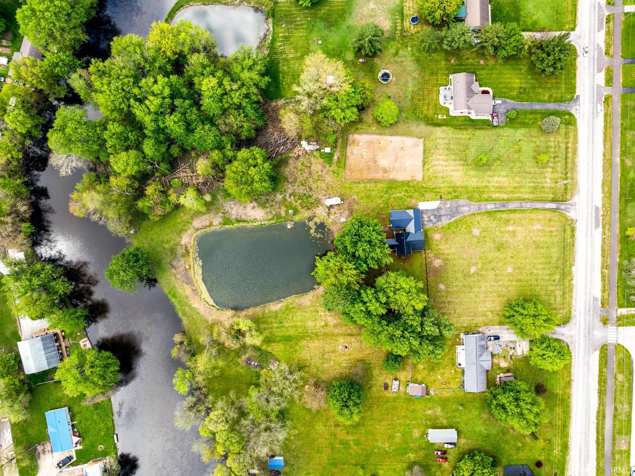 Expansive property featuring a pond, mature trees, and a substantial grassy area