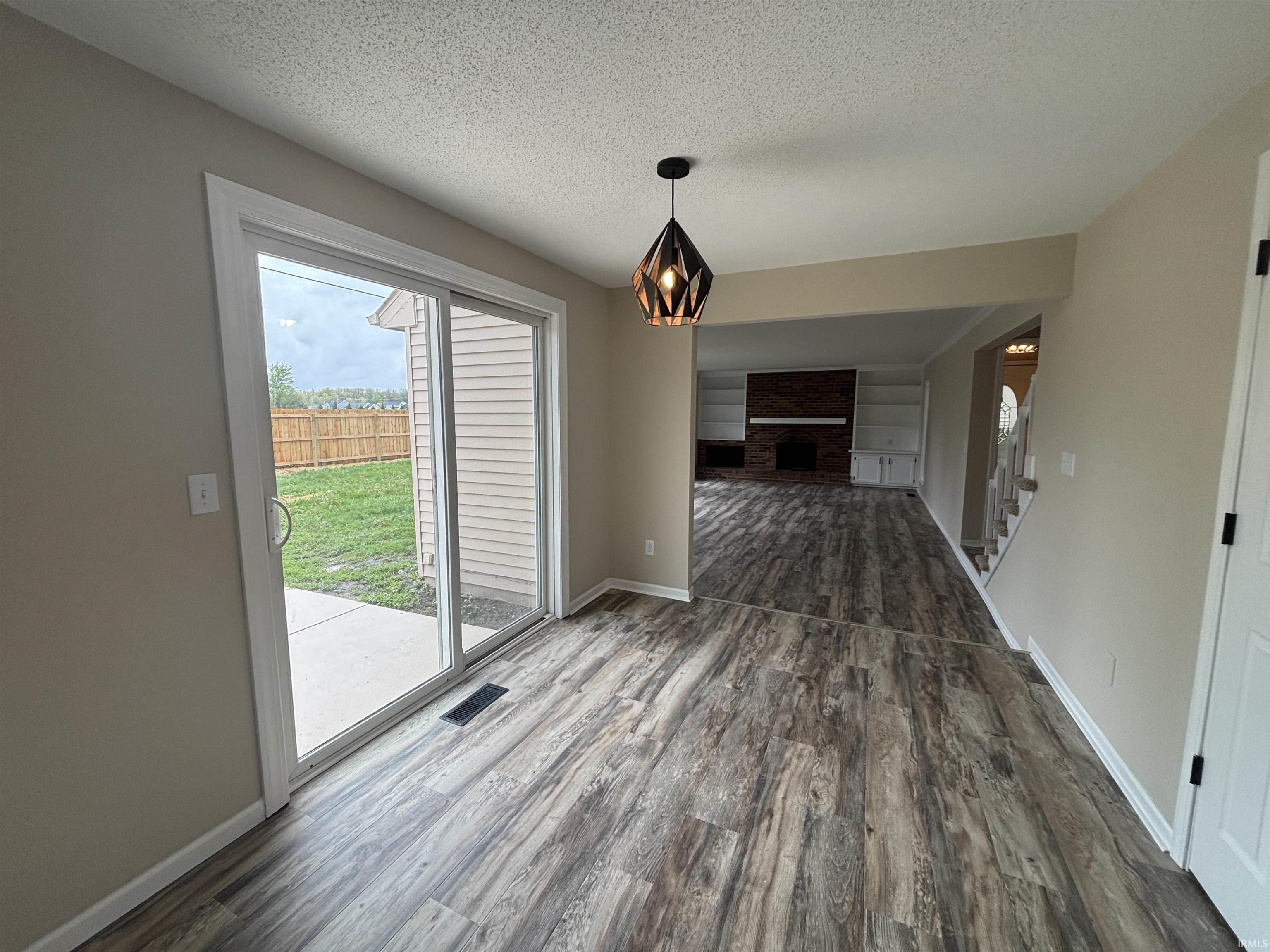 Dining area featuring wood-finish flooring, a contemporary pendant light fixture, and sliding glass doors