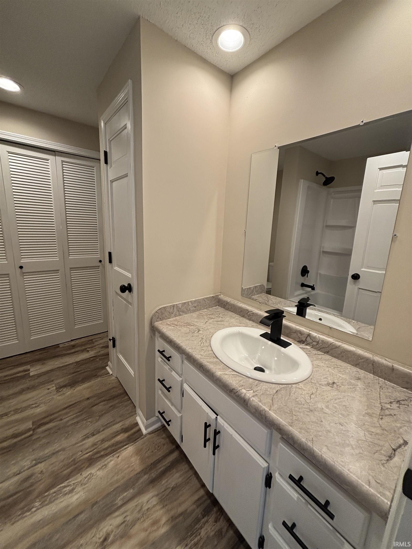 Bathroom vanity featuring a white oval sink with a matte black faucet, set against a stone-finish countertop