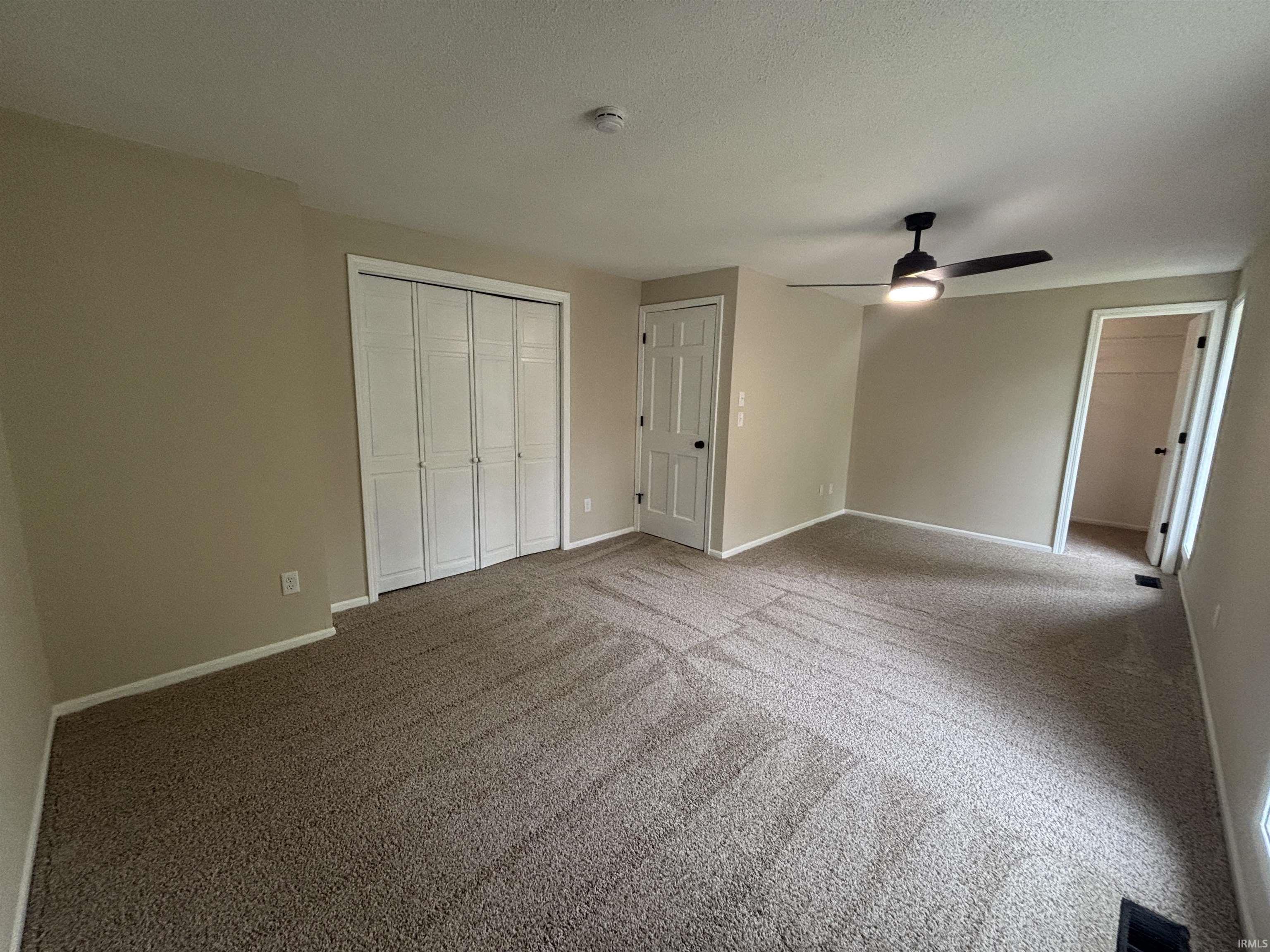 Spacious room featuring textured carpeting, neutral wall finishes, and white trim