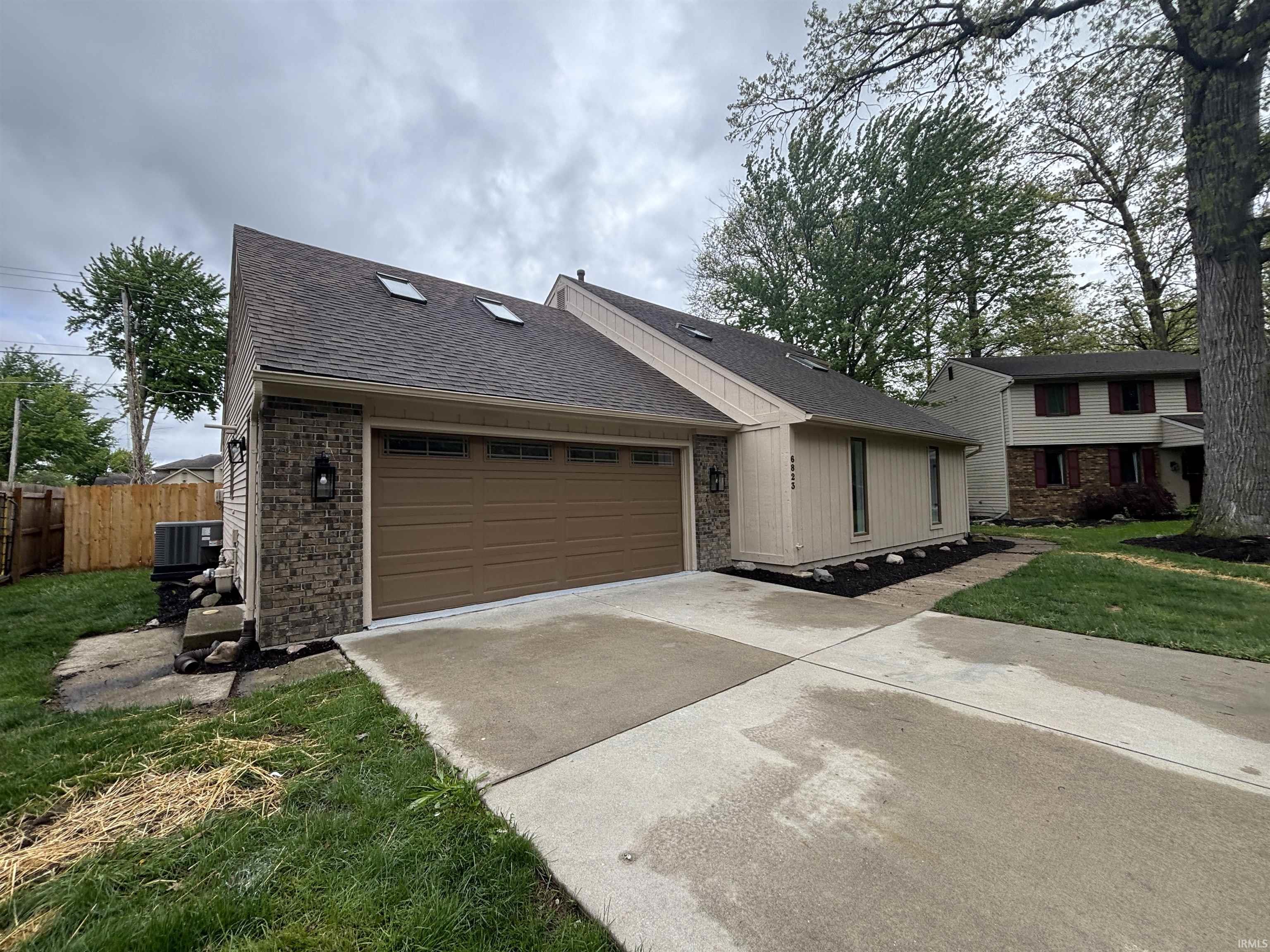 Contemporary exterior featuring a split-level roofline with skylights, an attached two-car garage with a panel door, and stone facade accents