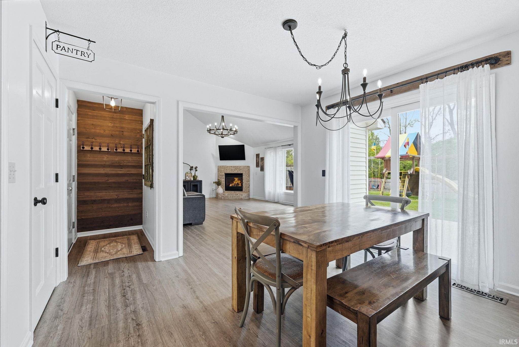Dining area featuring wood-finish flooring, a black chandelier, and sliding glass doors with a rustic wood valance