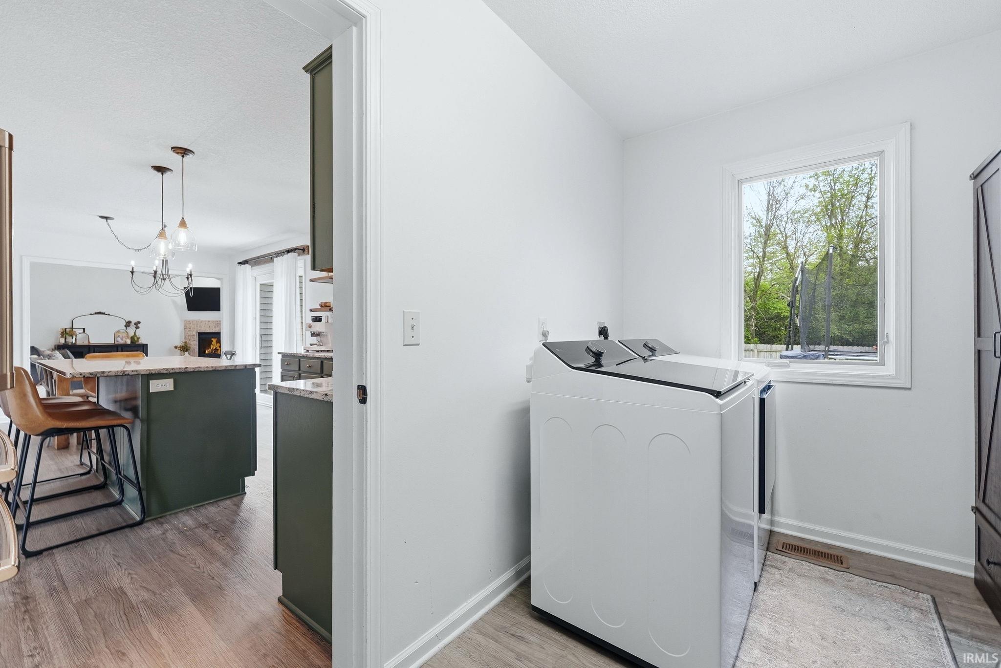 Dedicated laundry area featuring a window, wood-finish flooring, and a built-in storage cabinet