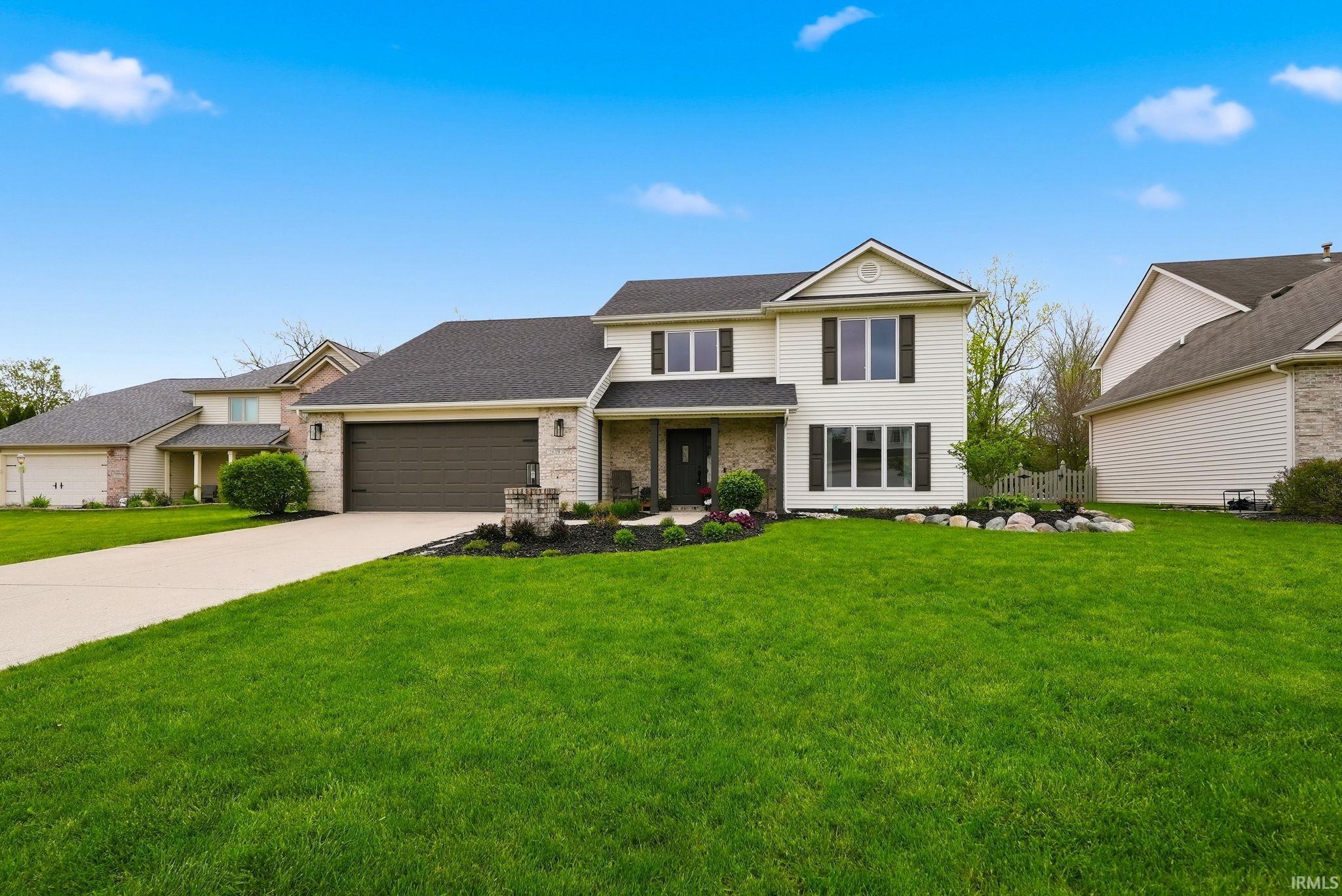Two-story exterior with light-colored siding, dark shutters, and a prominent front-facing garage with a dark door