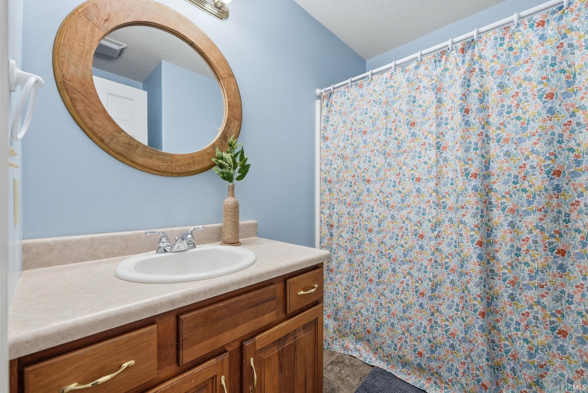 Bathroom vanity featuring a light-toned countertop with an integrated sink, wood-finish cabinetry, and chrome fixtures
