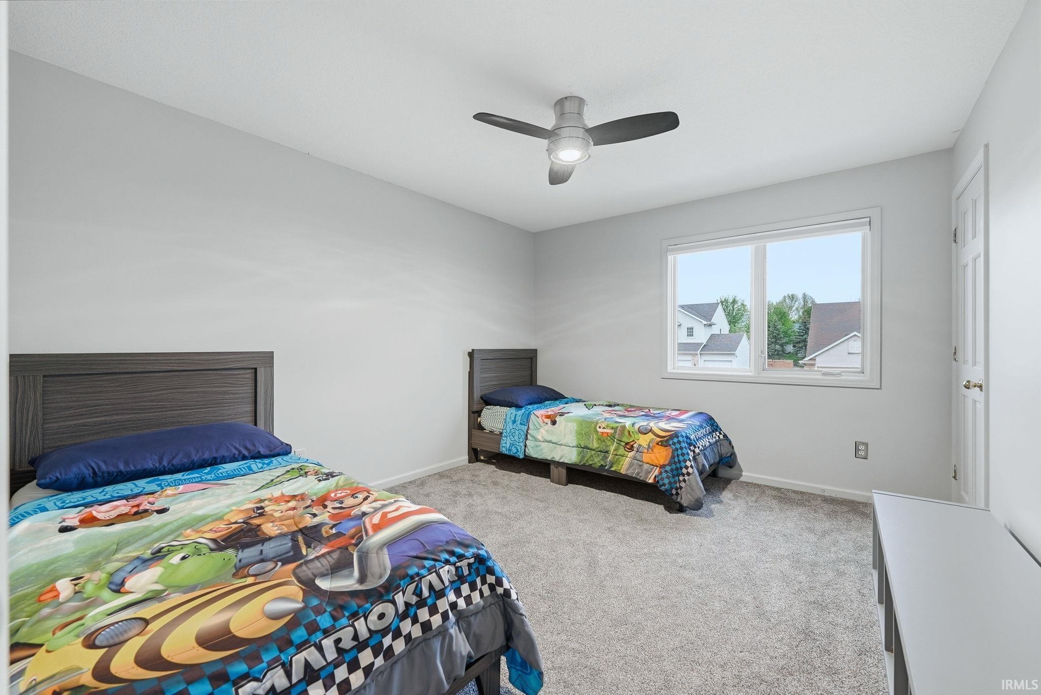 Bright room featuring neutral wall paint, gray carpet, a white framed window, and a ceiling fan with integrated lighting