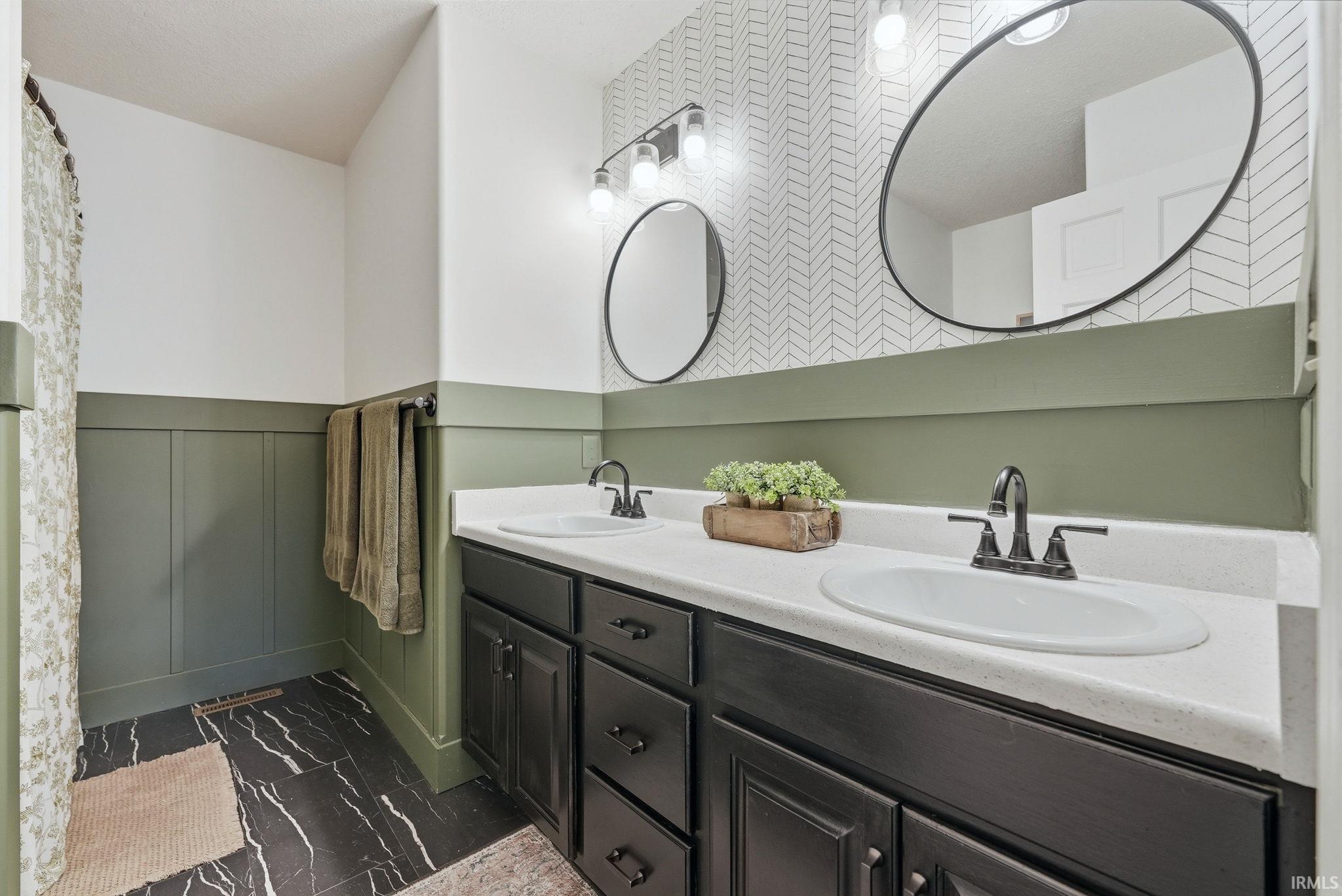 Double vanity featuring white oval sinks, dark cabinetry, and coordinating black hardware