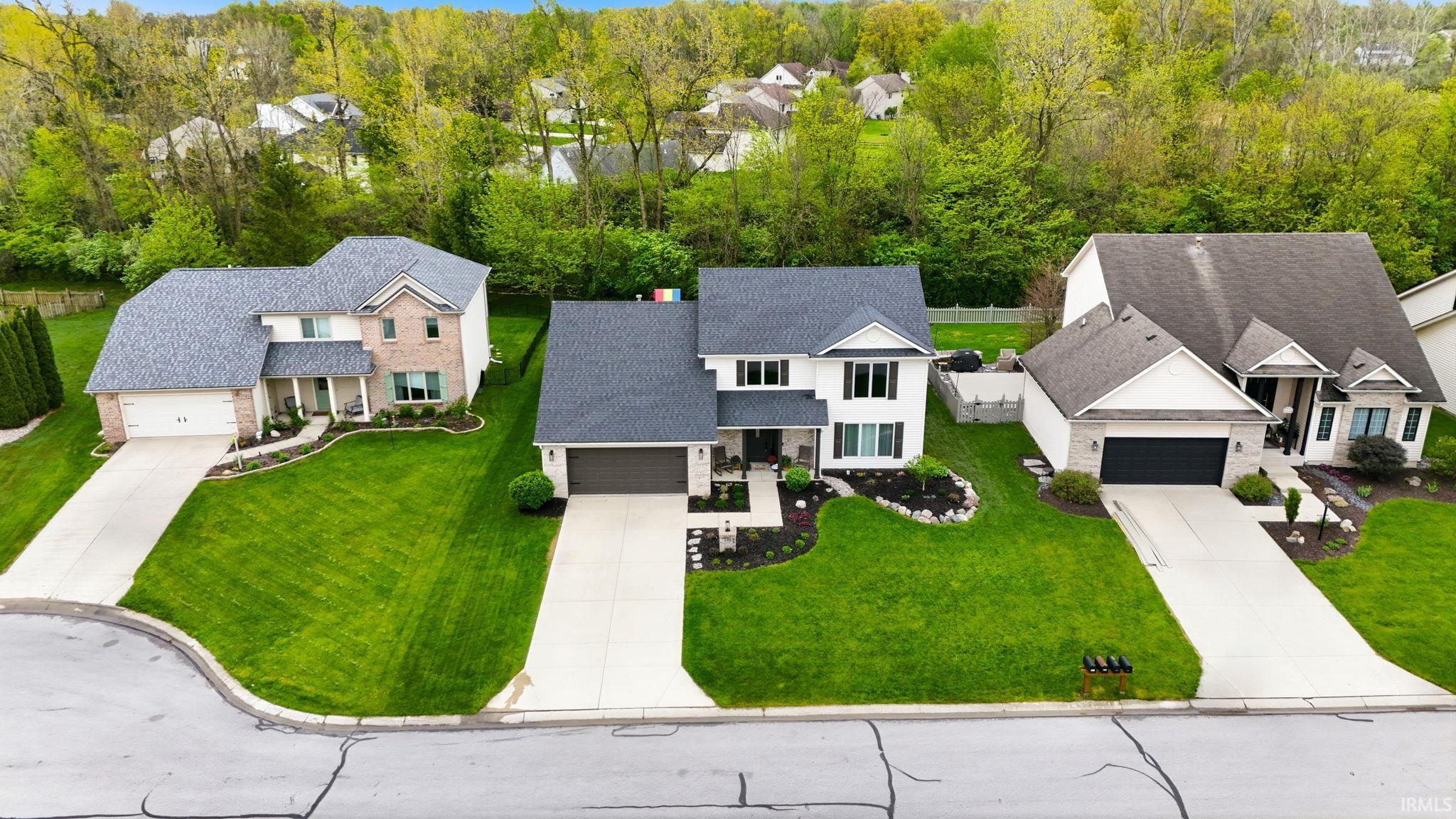 Traditional two-story residence featuring a white facade with black window shutters, a dark gray shingled roof, and an attached two-car garage