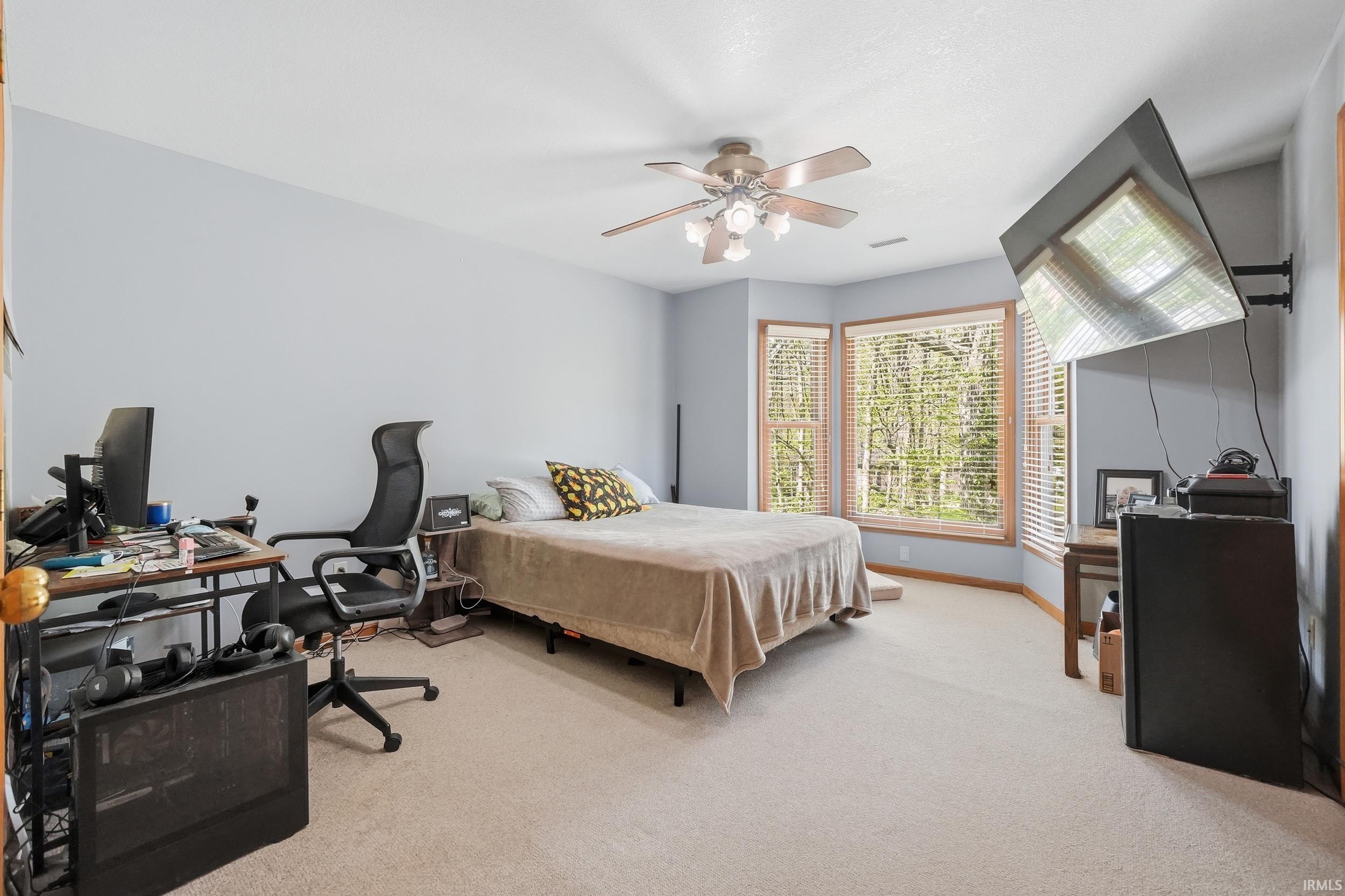 Bay window with wood trim, ceiling fan light fixture, and carpet flooring