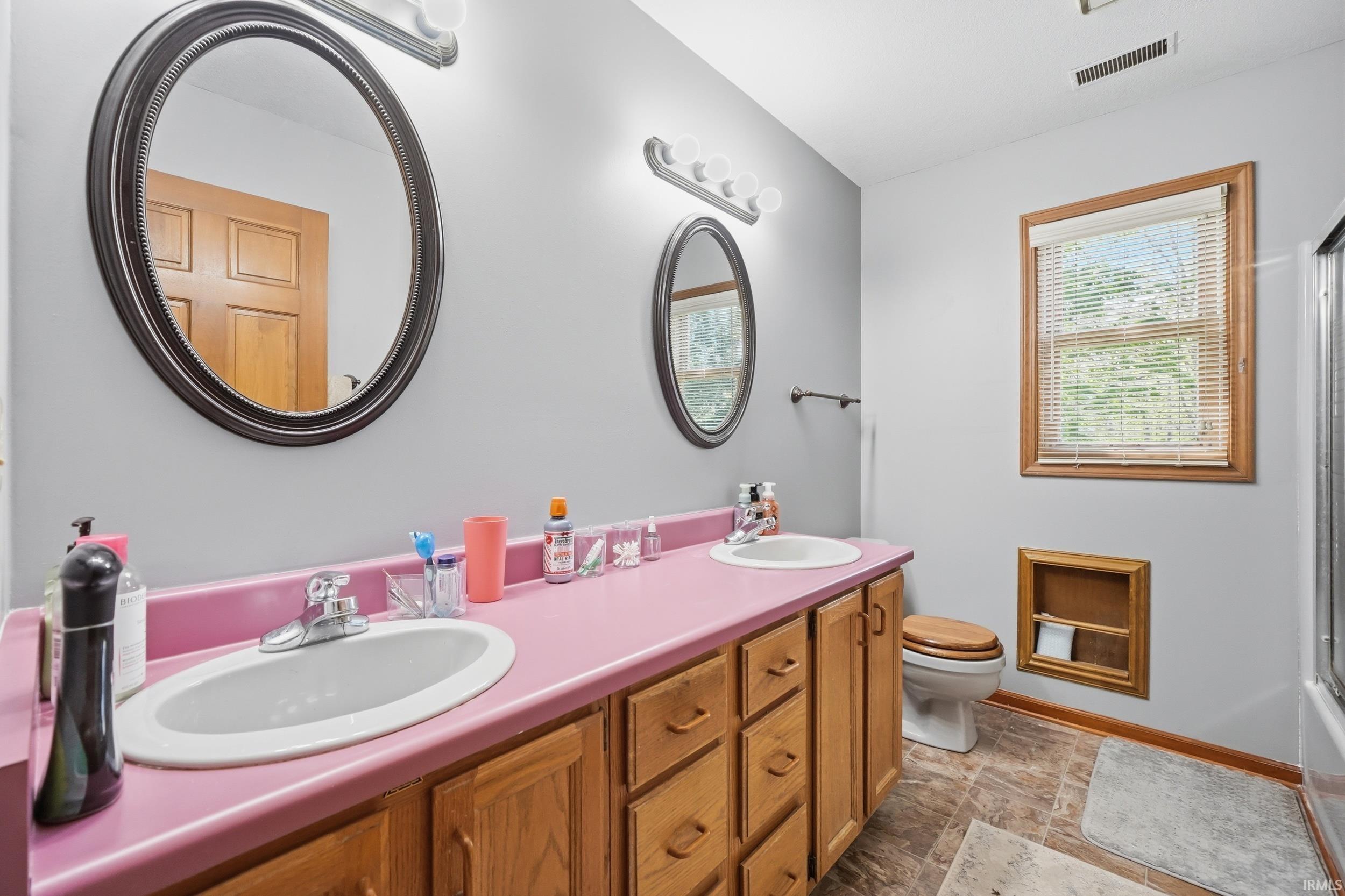 Double vanity with integrated sinks, framed mirrors, and wood cabinetry